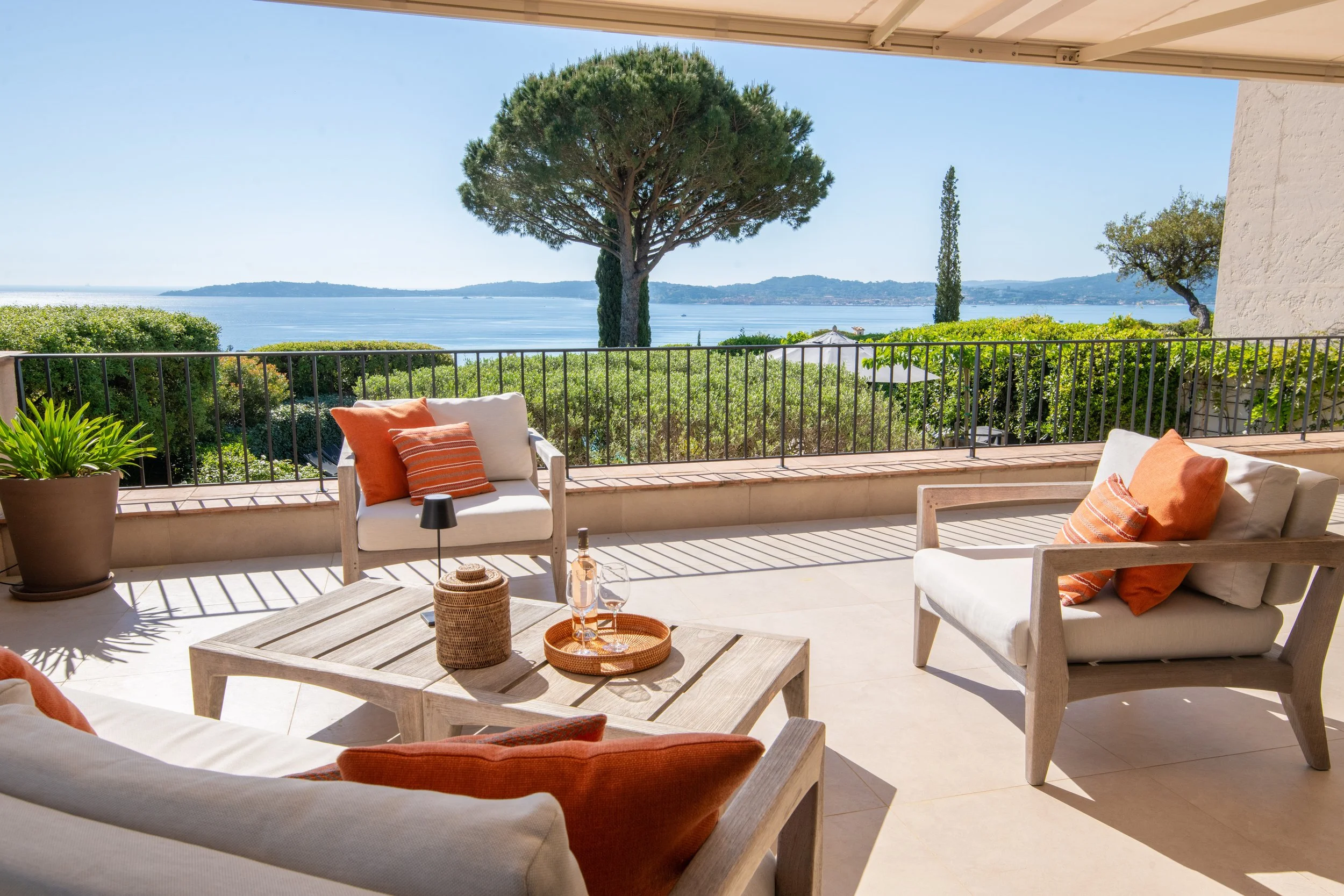 Vue sur la mer avec piscine, table à manger extérieure, parasol fermé, et pin parasol en arrière-plan.