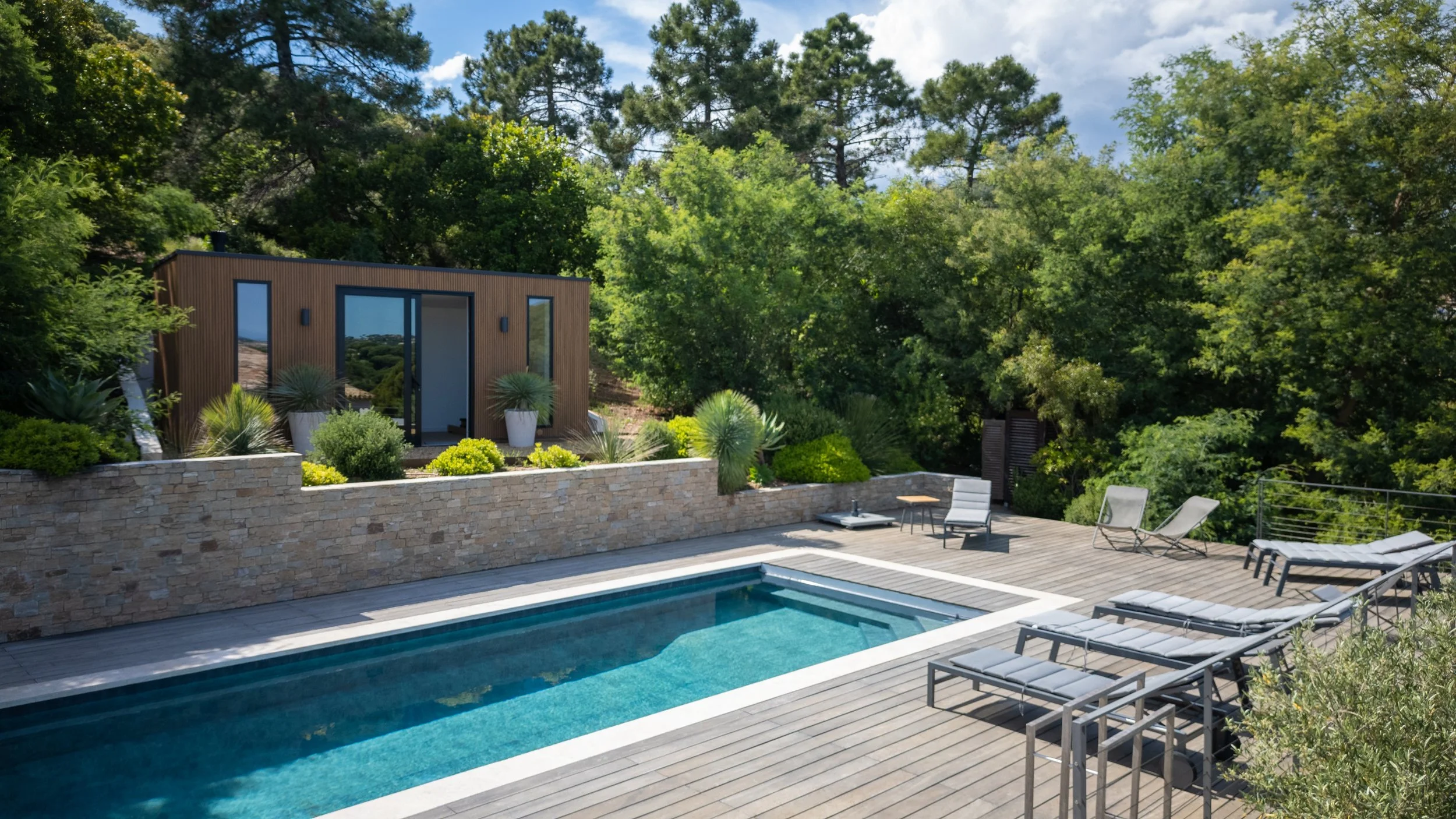 Vue panoramique depuis une terrasse avec mobilier de jardin en rotin, palmiers, mer et ciel bleu en arrière-plan.