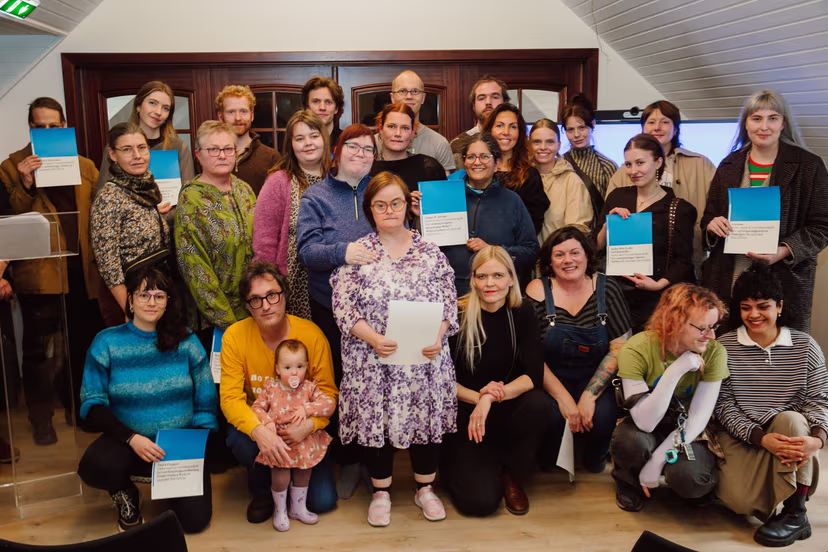 Group of diverse people gathered in a room, some holding certificates, posing for a photo.