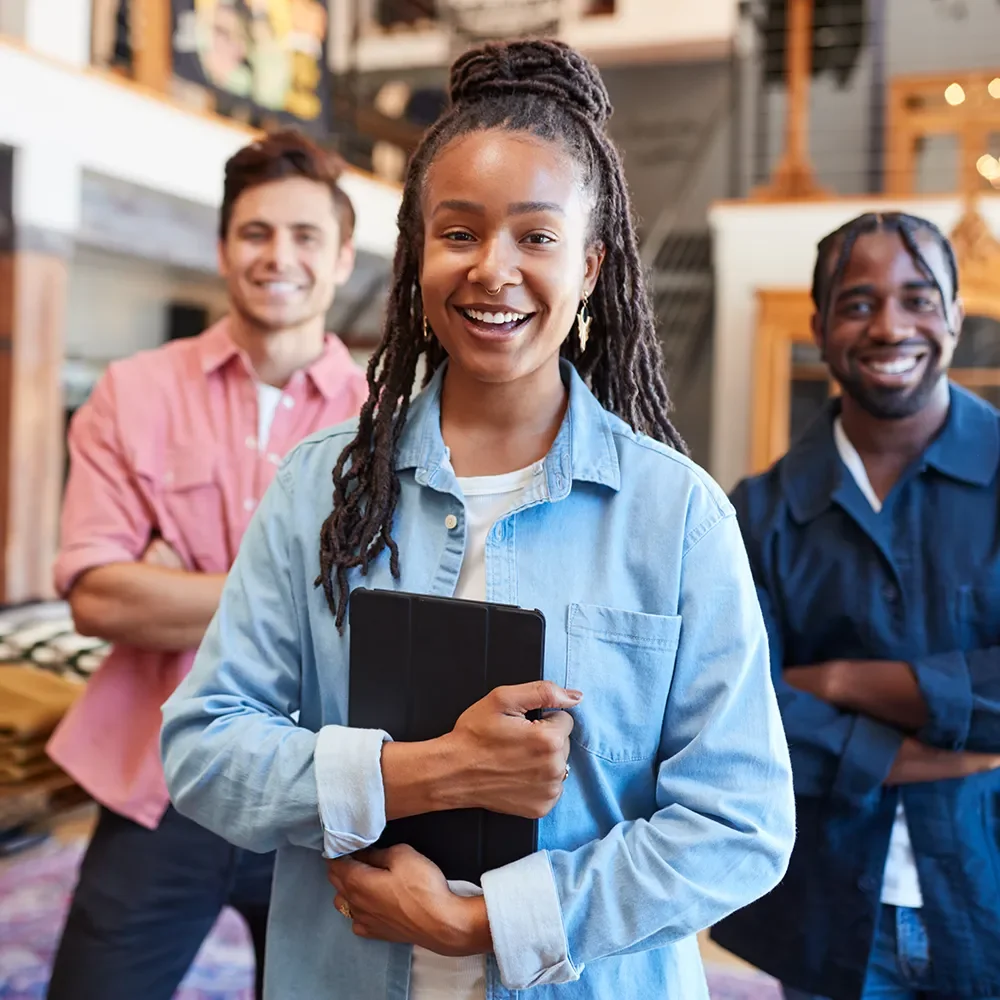 Three retail shop assistants smiling at the camera in a clothing shop