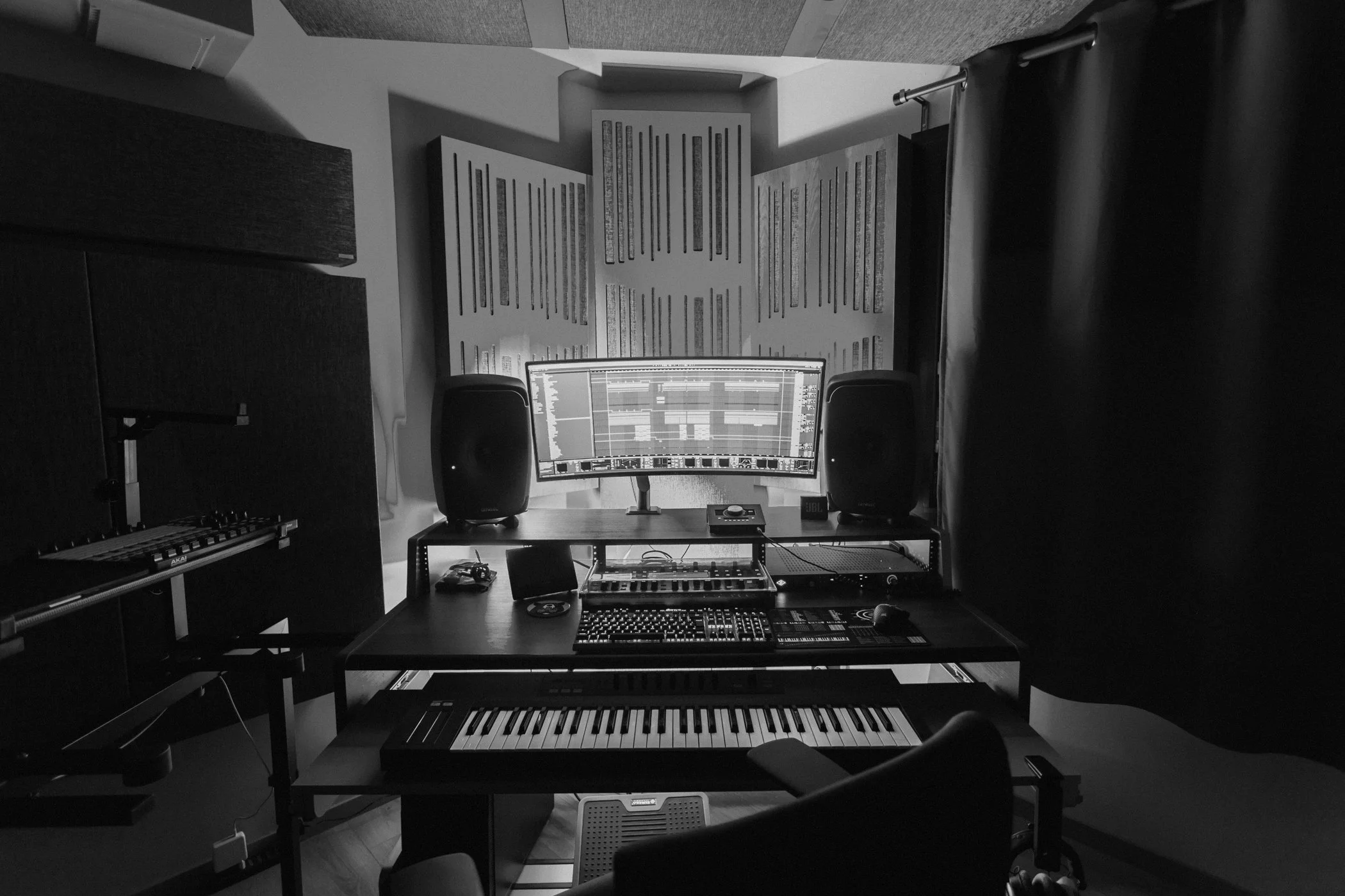 Matteo Tura's music production studio with a curved monitor, audio speakers, keyboard, and musical equipment in a dimly lit room.