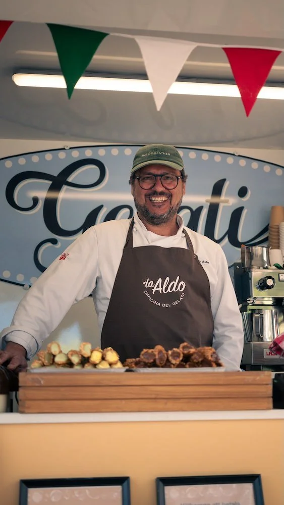 Glad man i förkläde och keps i en food truck för glass.