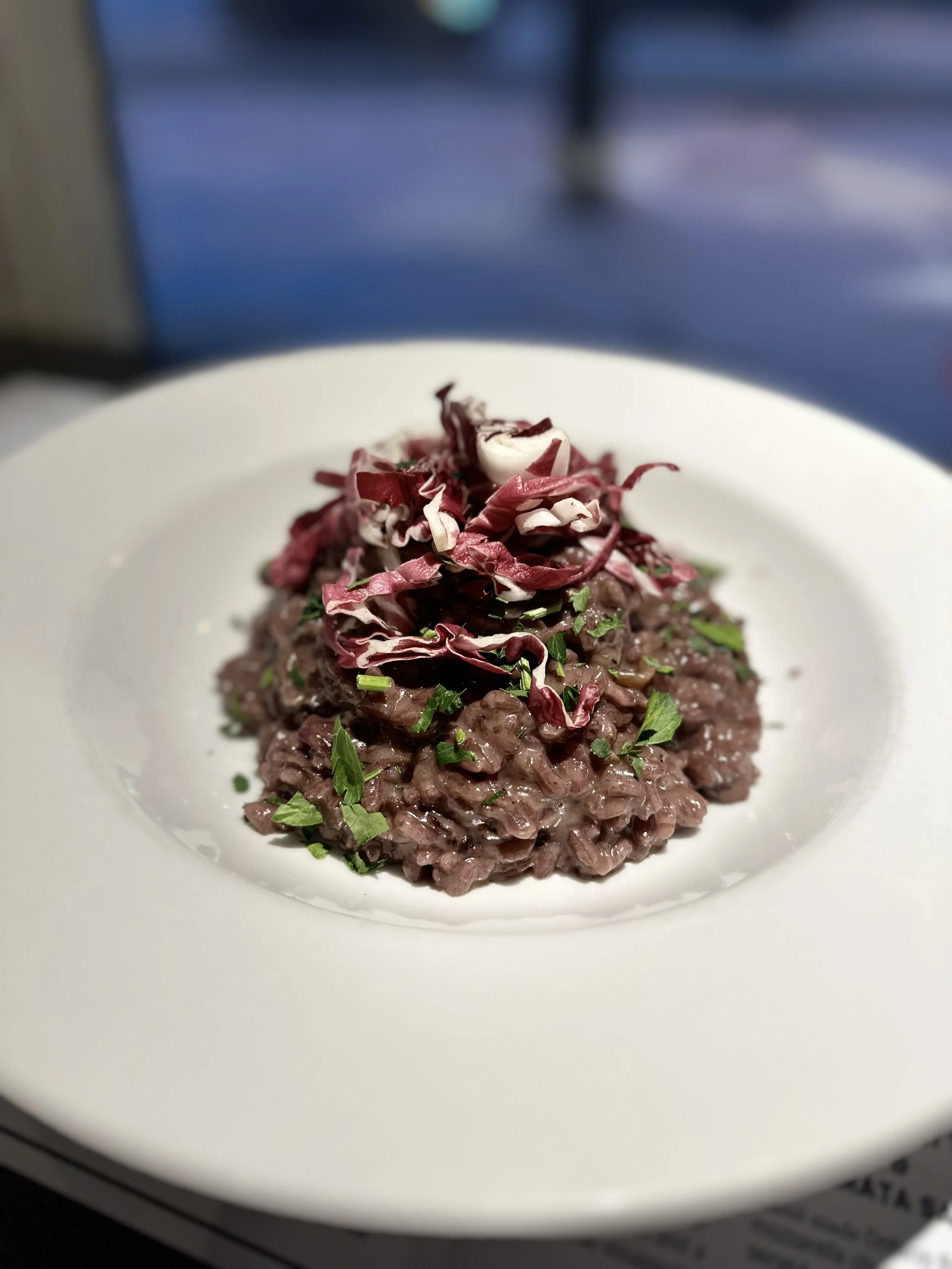 A plate of risotto garnished with chopped herbs and radicchio.