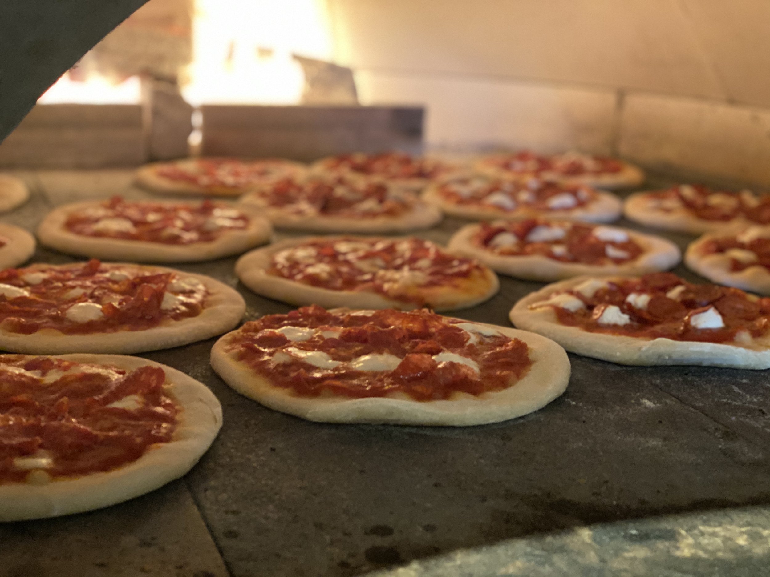 Mini pizzas with tomato sauce and cheese baking inside an oven.