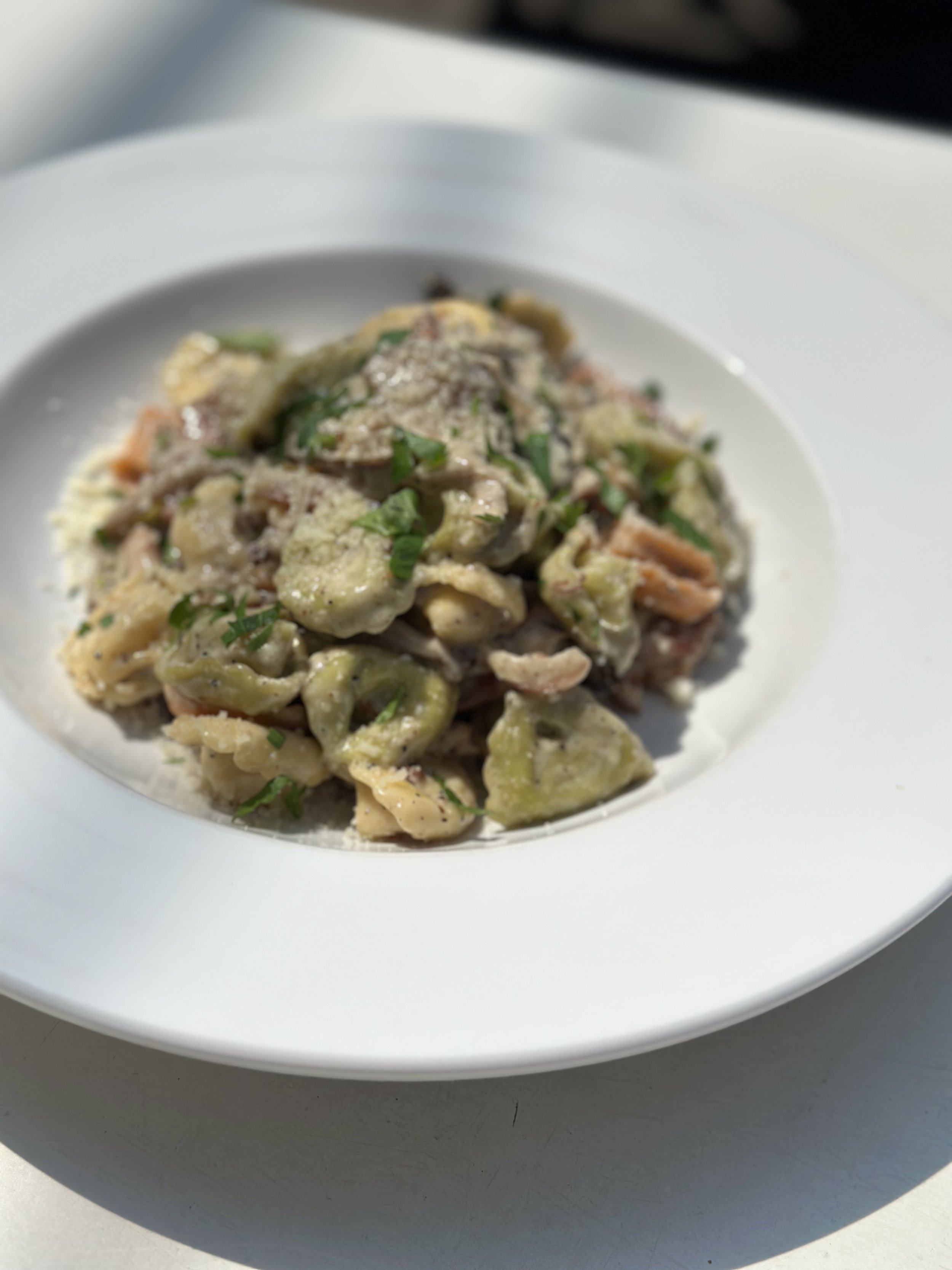 A plate of gnocchi pasta with green sauce, garnished with chopped herbs.