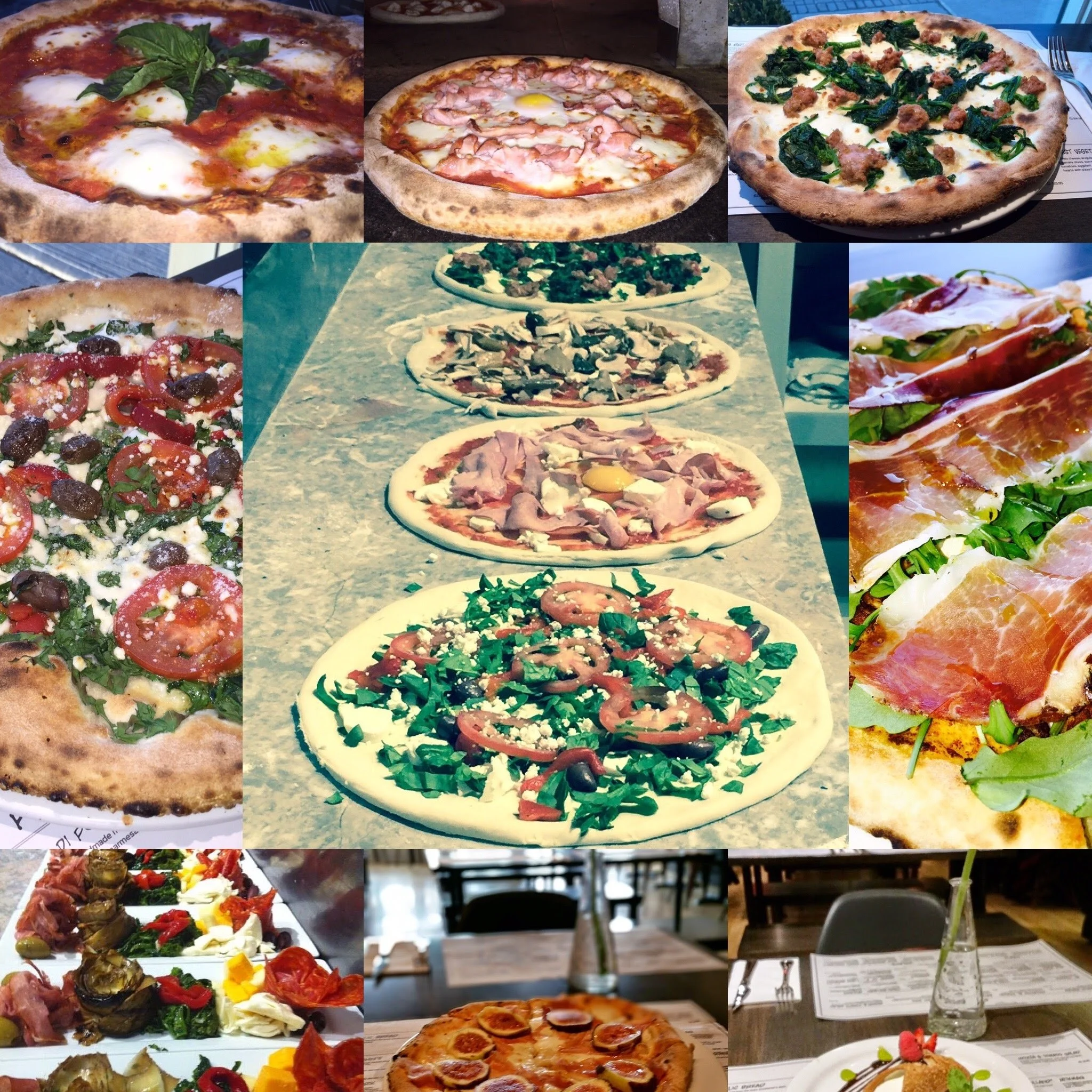 Assorted pizzas with various toppings including basil, ham, spinach, tomatoes, olives, prosciutto, and mushrooms, displayed at a restaurant or pizza shop.
