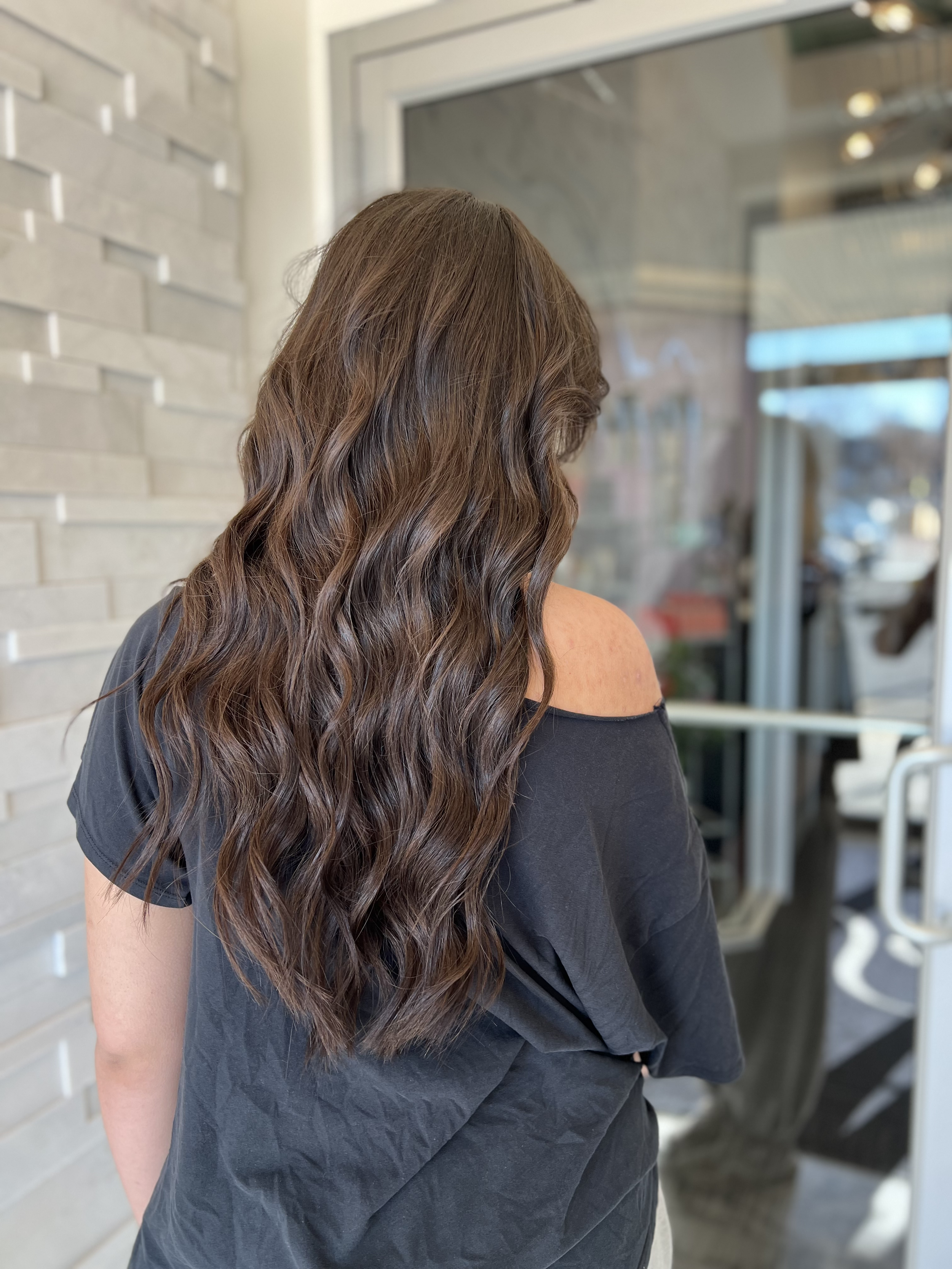 women with long dark wavy hair wearing weft hair extensions.