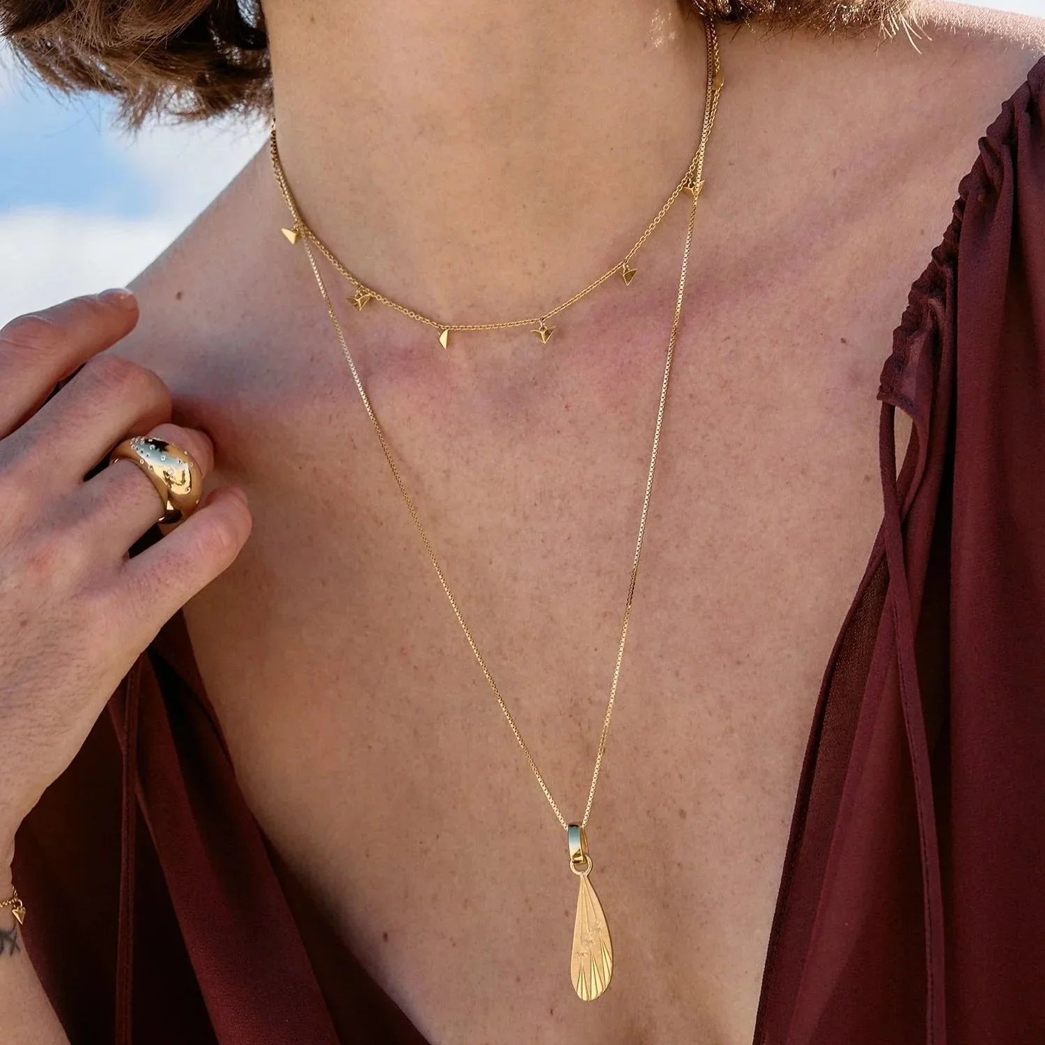 Close-up of the Dreamer Celestial Wing Necklace by Rachel Jackson, styled layered with fine gold chains to highlight the star-detailed wing pendant and elegant everyday wear.