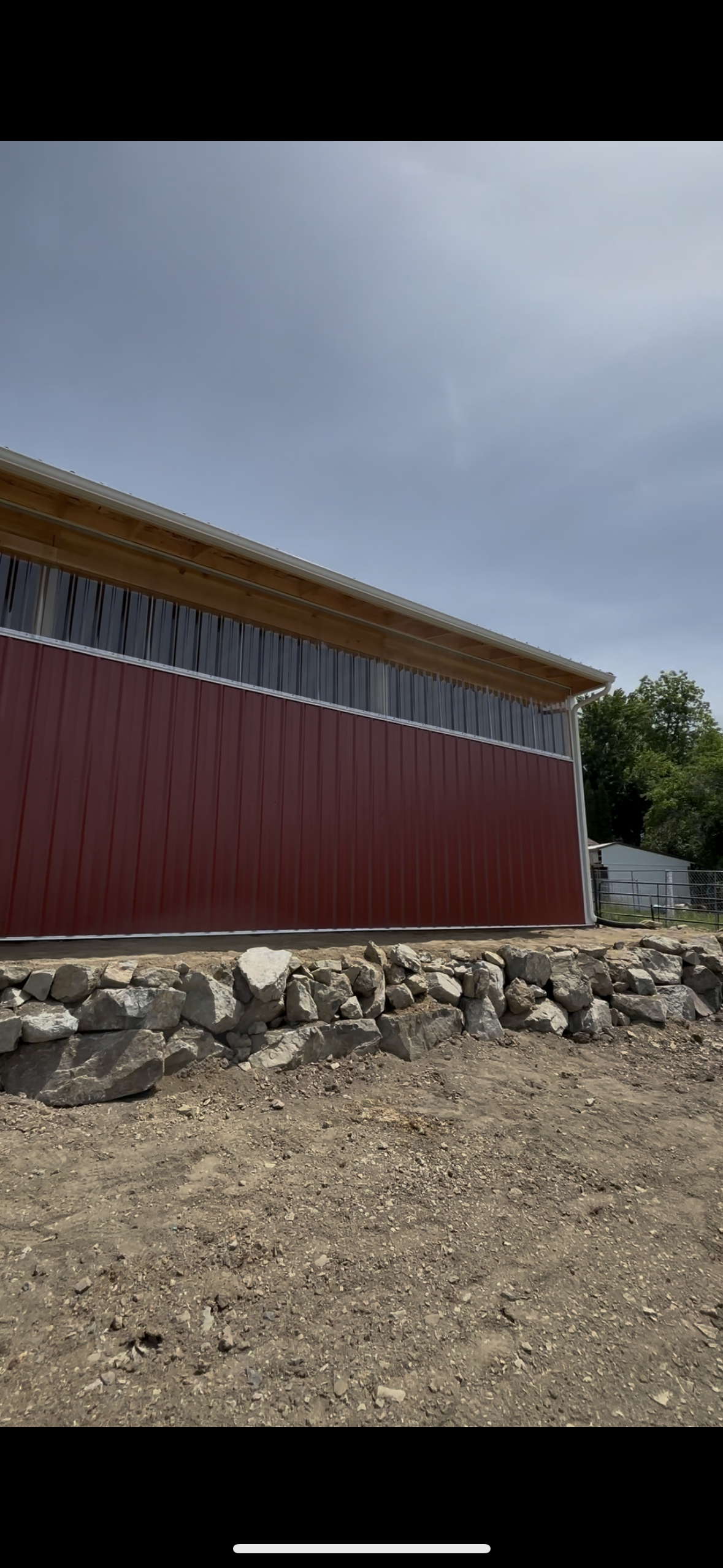 Modern wooden house in mountainous landscape with large window, surrounded by greenery.