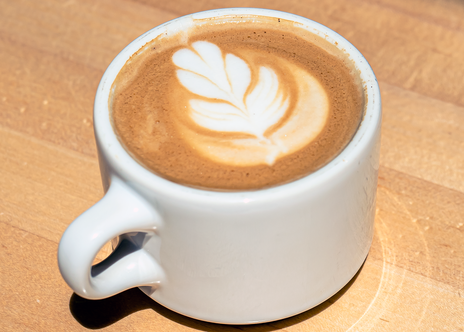 Latte with heart-shaped latte art in creamy steamed milk.