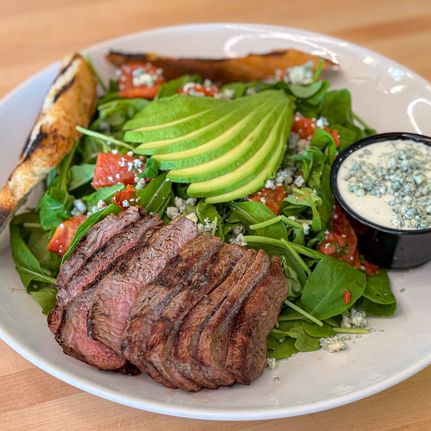 Salad with steak, avocado, blue cheese and grilled bread.