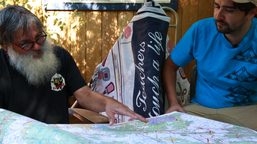 Floyd Buckskin (left) sits with Sky Scholfield (right) pointing at a map