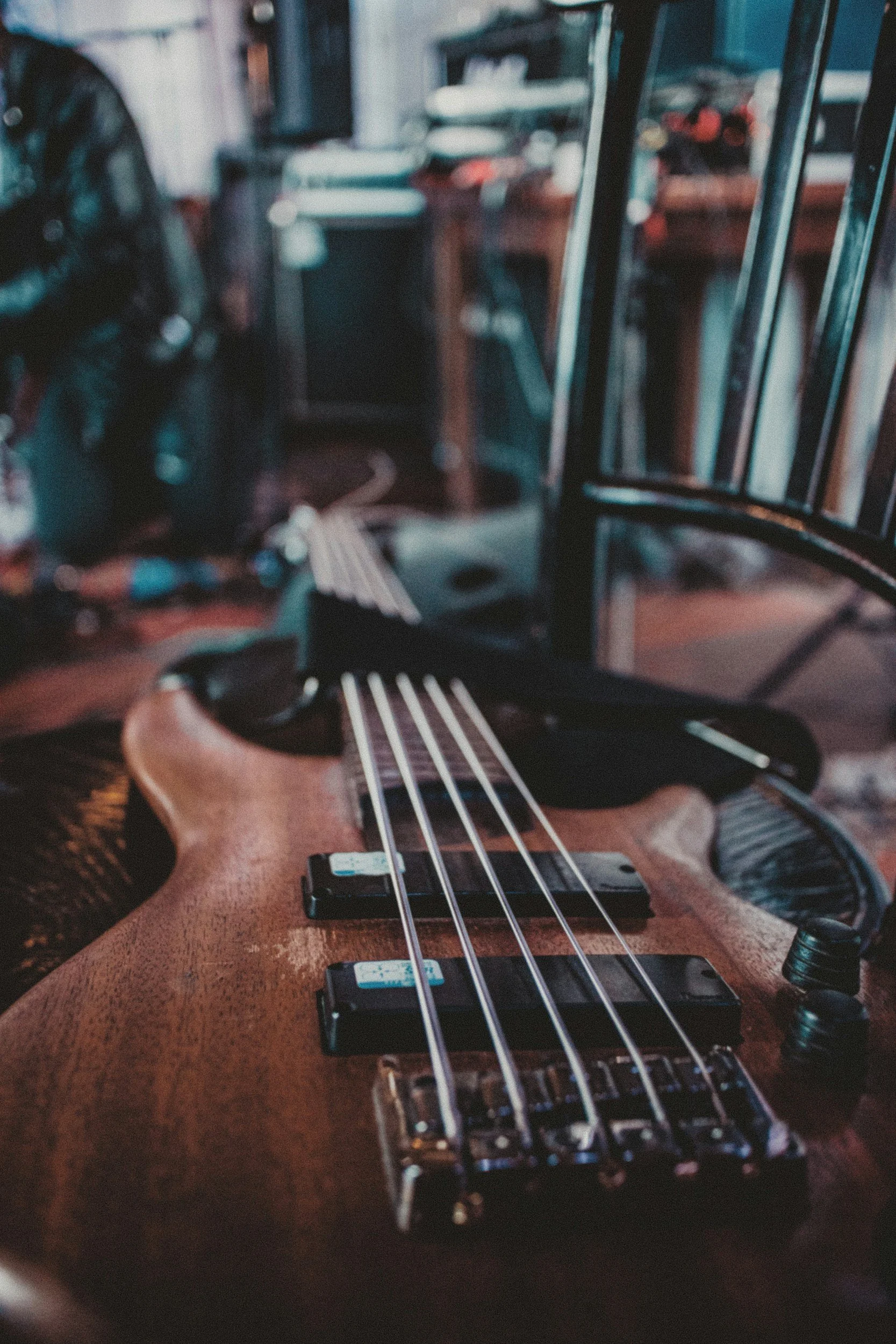 Close-up of an acoustic bass guitar resting on a chair in a music studio with various musical equipment and furniture in the background.
