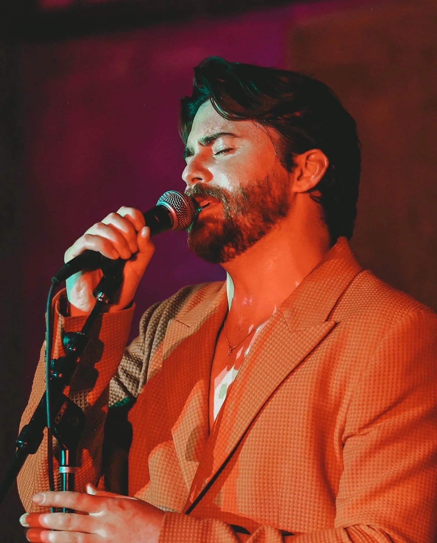 Cornelius Versa singing into a microphone on stage in Los Angeles