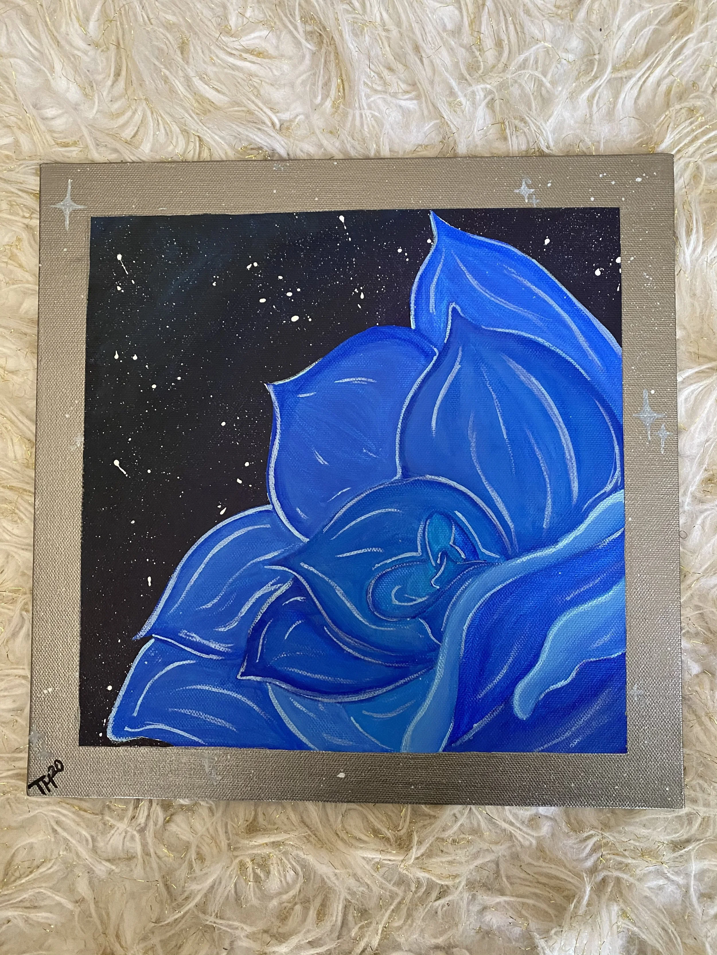 A painting of a large blue rose against a black starry background with white splatters and metallic gold and silver border.