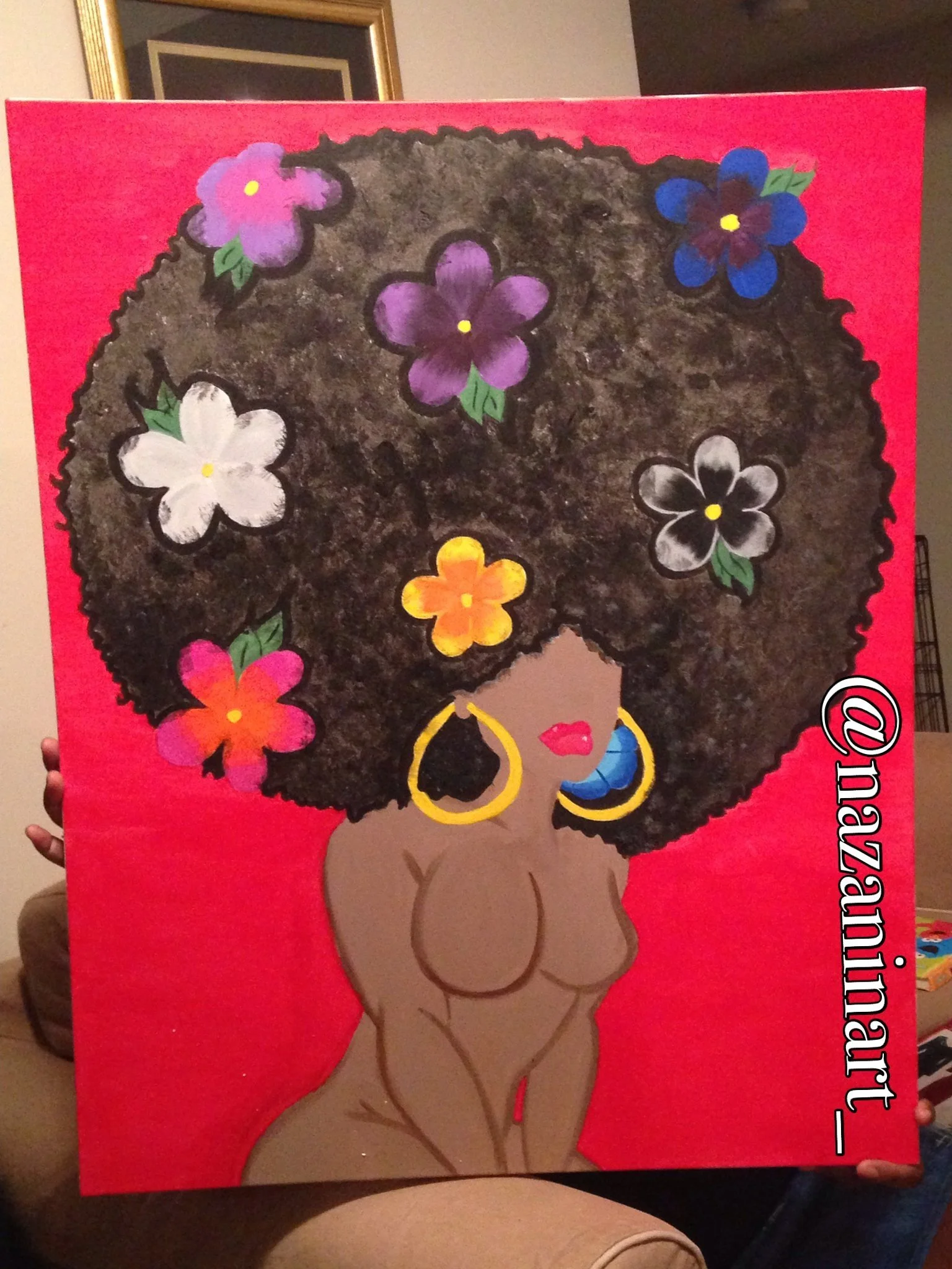 A painting of an illustrated woman with dark skin and large, textured Afro hair adorned with colorful flowers against a red background. The woman has large gold hoop earrings, pink lips, and a blue earring. The artist's Instagram handle, @nazanuit, is written on the lower right corner.