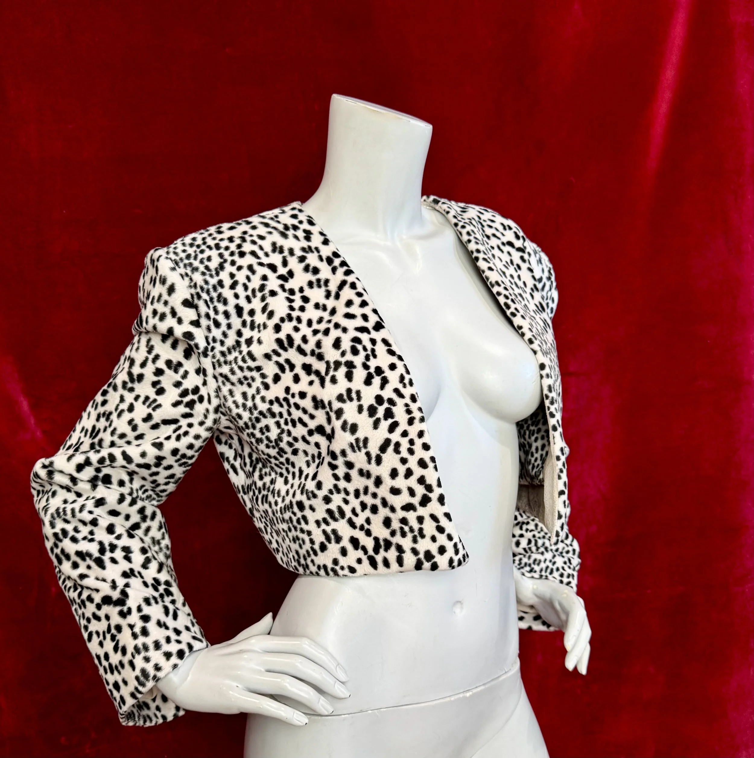 cropped women's jacket with strong shoulder line, long sleeves, in off-white with black spots faux fur (low pile).