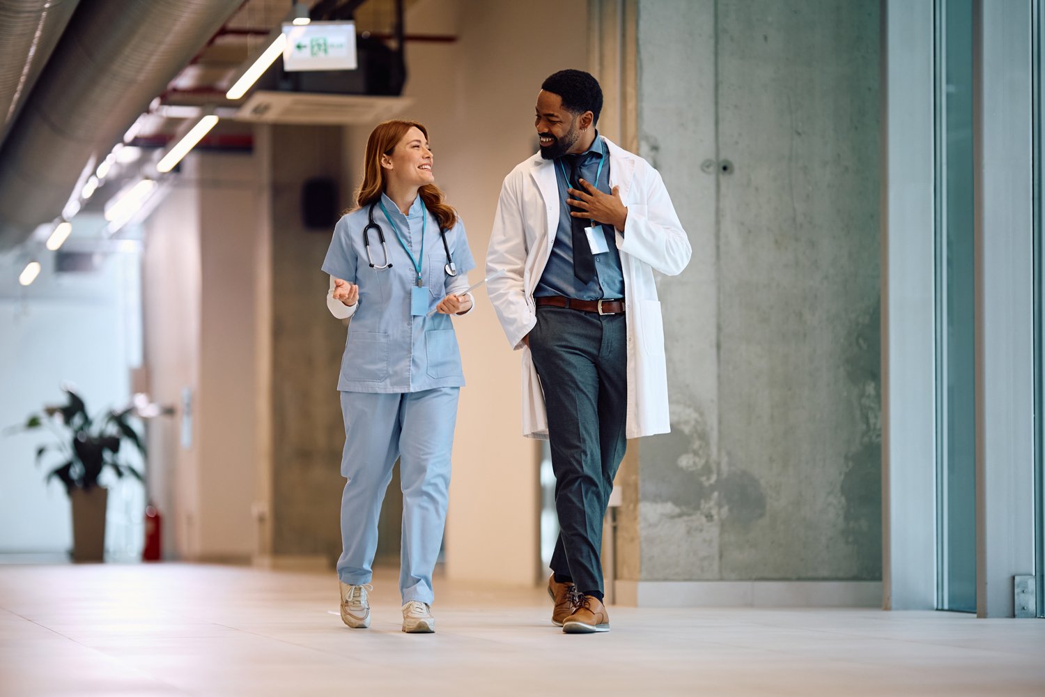 Two medical professionals walking through modern hallway at healthcare facility