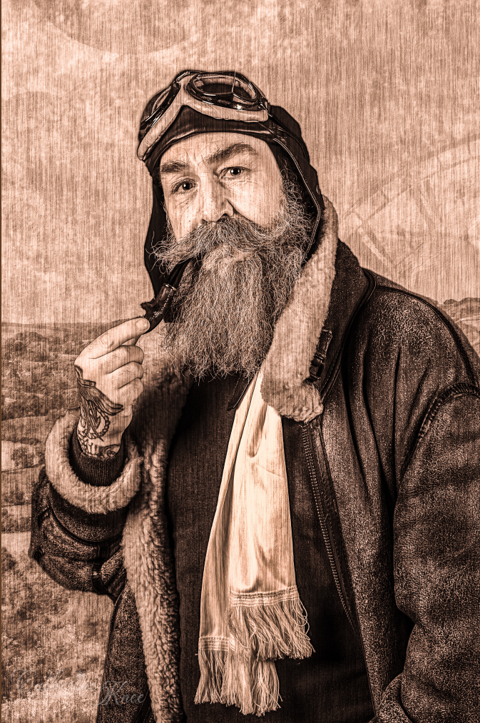 Front cover of sepia toned notebook with bearded aviator in leather cap, goggles, and shearling jacket holding a pipe