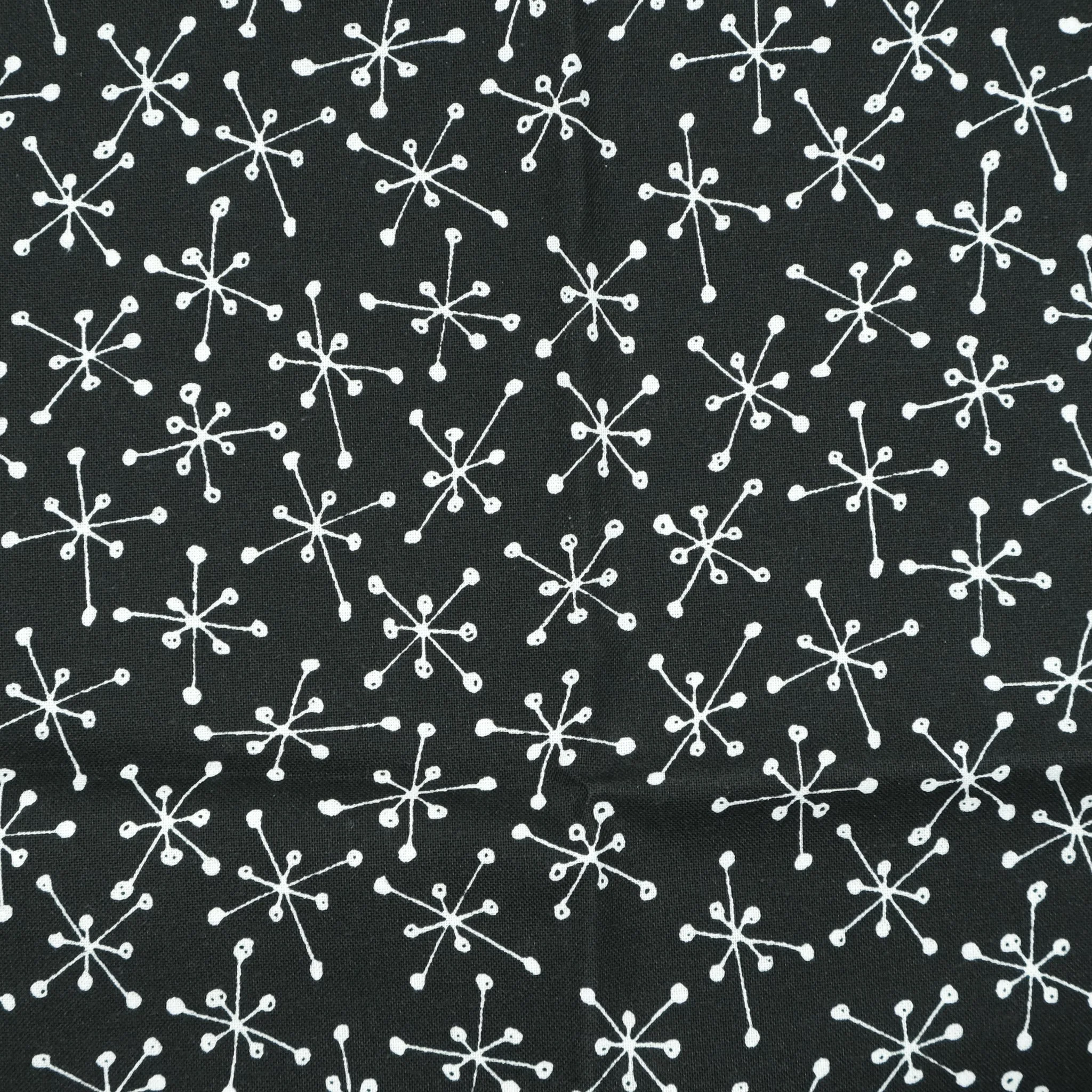 Fabric close up showing white atomic starbursts on black background, used for handmade Axis Range scrunchie by Creatoria Nyx