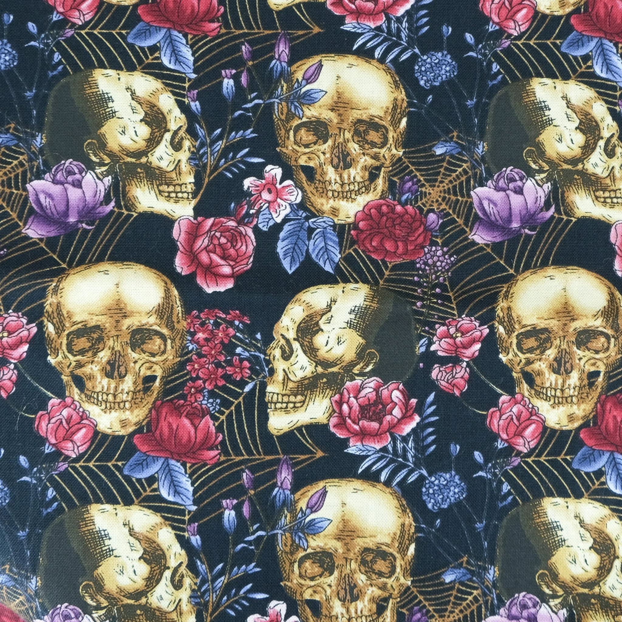 Fabric close up showing gold skulls with roses and webs on black background, used for handmade Axis Range scrunchie by Creatoria Nyx