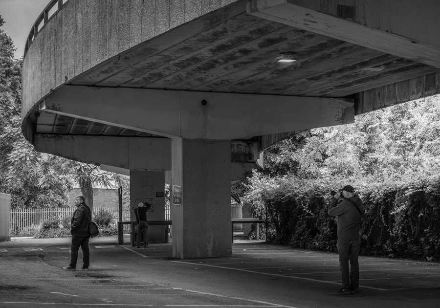 Three photographers exploring architectural compositions beneath Coventry's ring road during a summer photo walk.