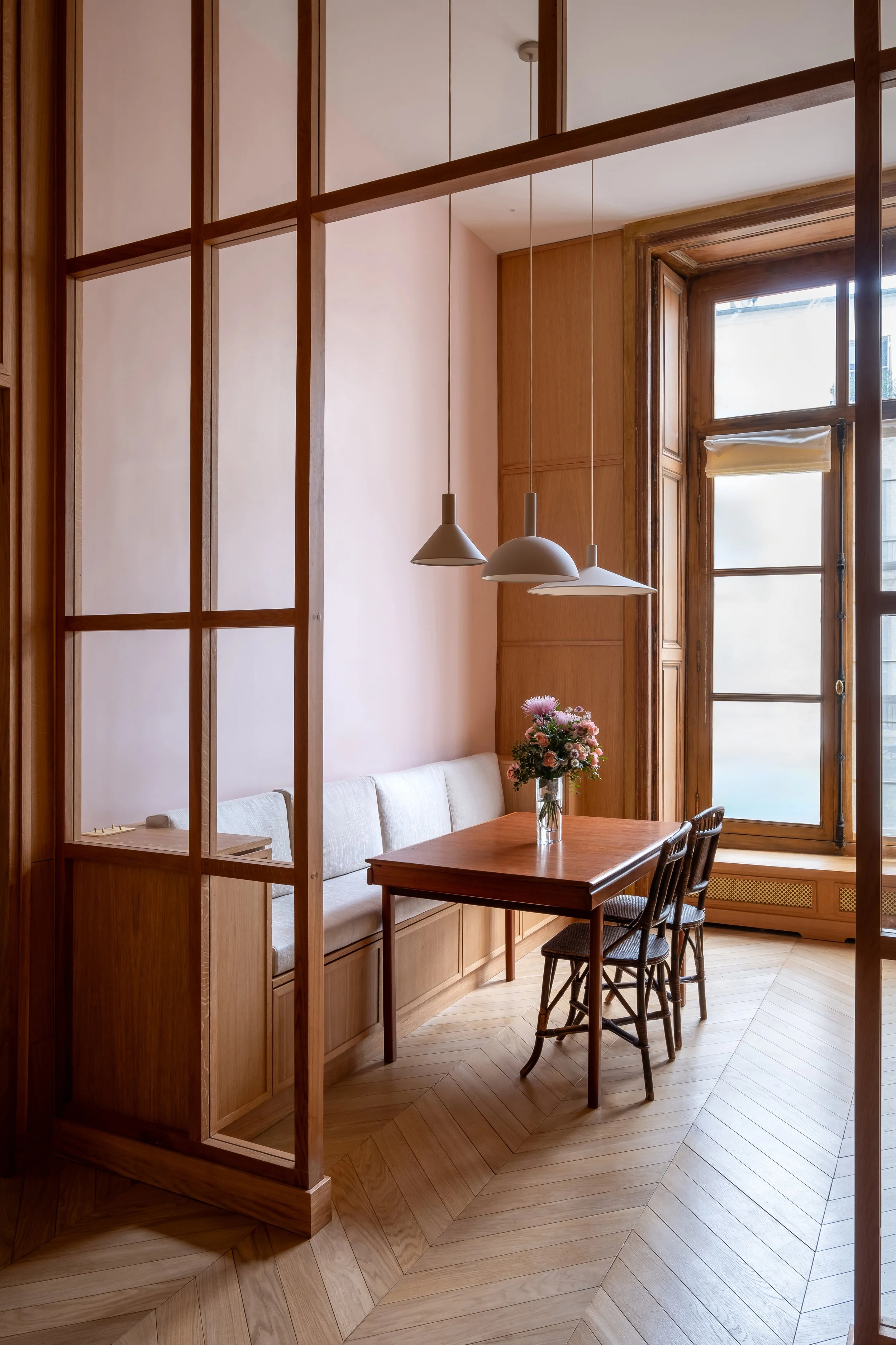 Vue depuis la verrière, coin repas lumineux, boiseries haussmanniennes d'origine rénovées, parquet point de Hongrie, chaise rotin, appartement Paris.