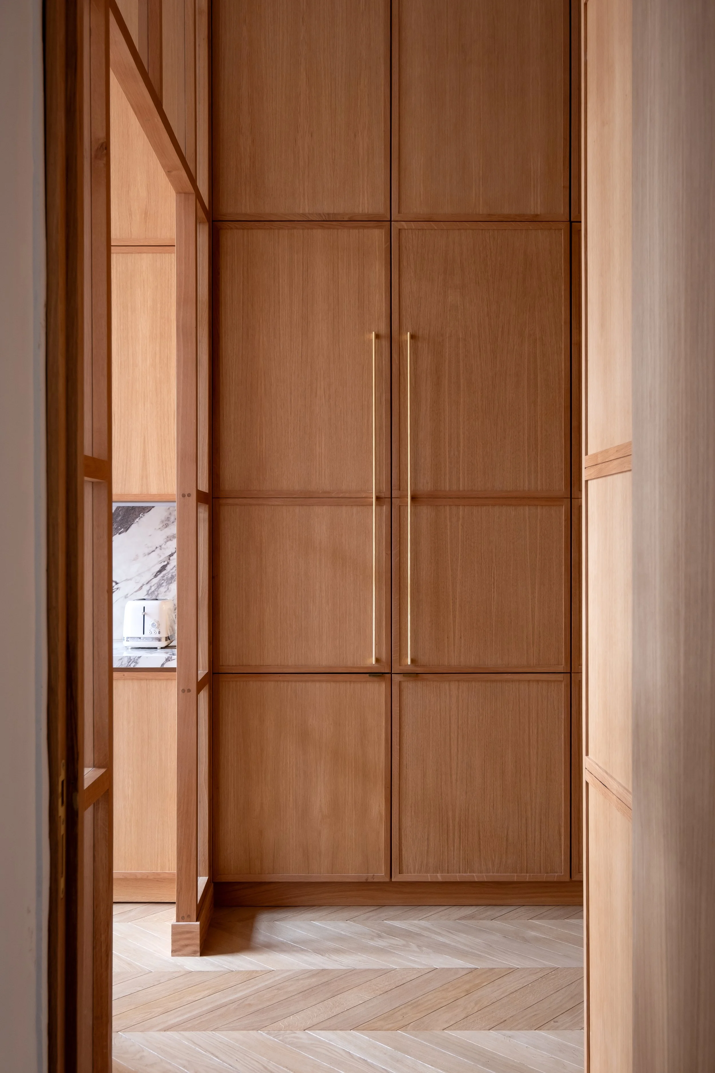 Verrière chêne sur mesure, poignées élancées laiton brossé, menuiserie pleine hauteur, univers élégant tout en chêne, appartement haussmannien Paris