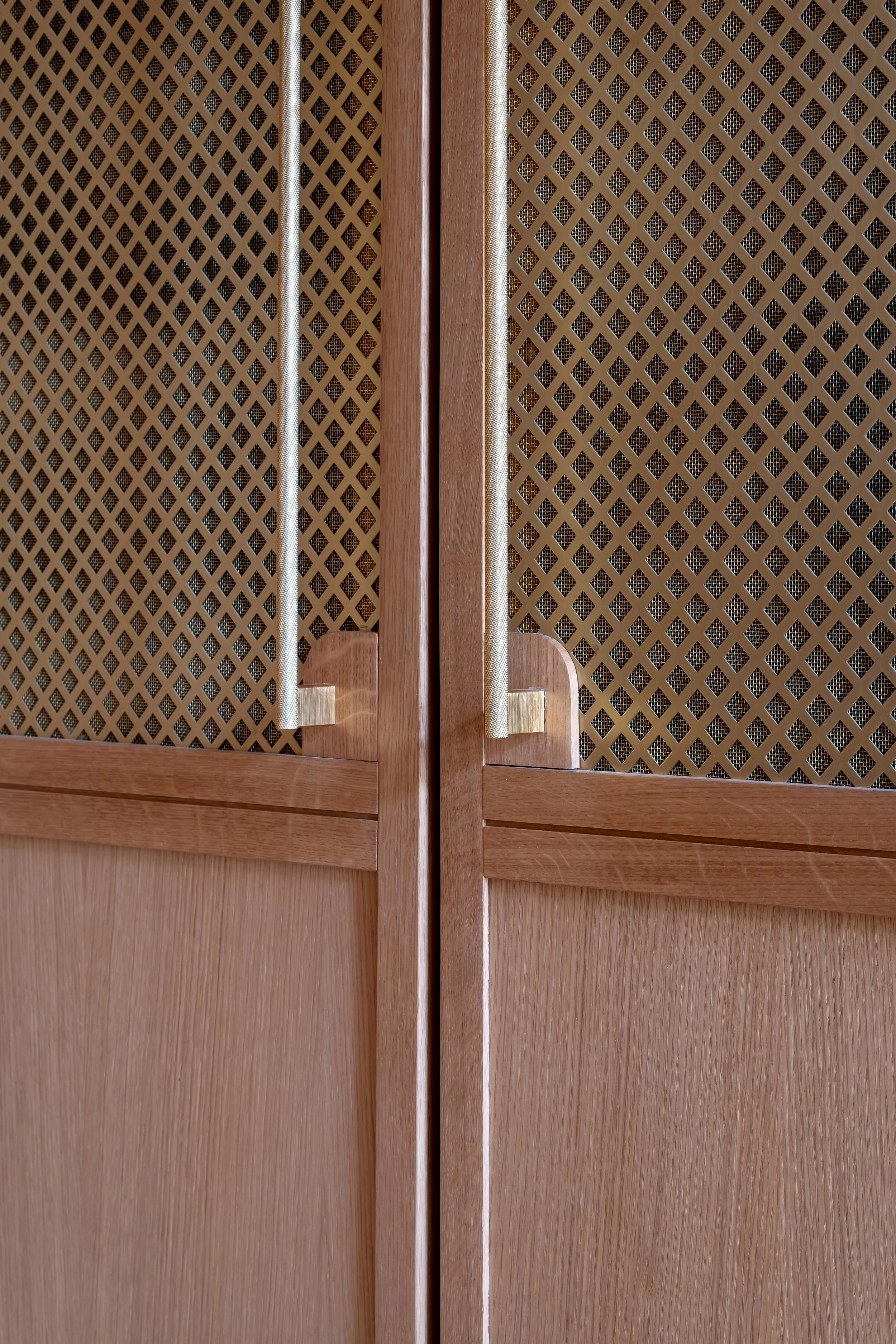Menuiserie chêne sur mesure, poignées fines laiton brossé, grille aération laiton, cohérence des matières jusqu'au dernier détail, appartement Paris.