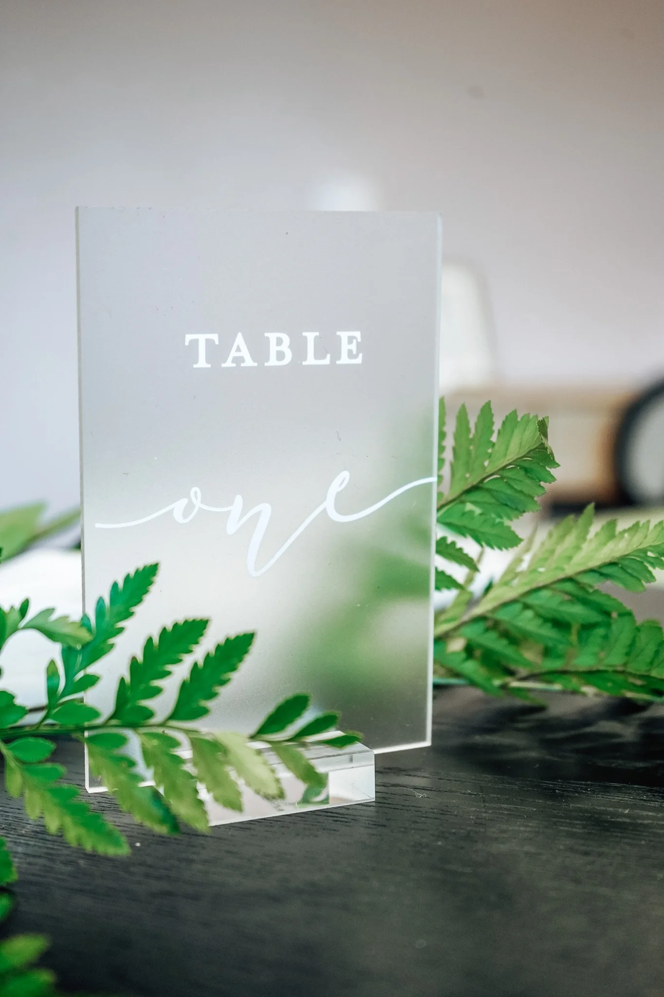 Cleear table number sign reading "table" in block letters and "one" in cursive