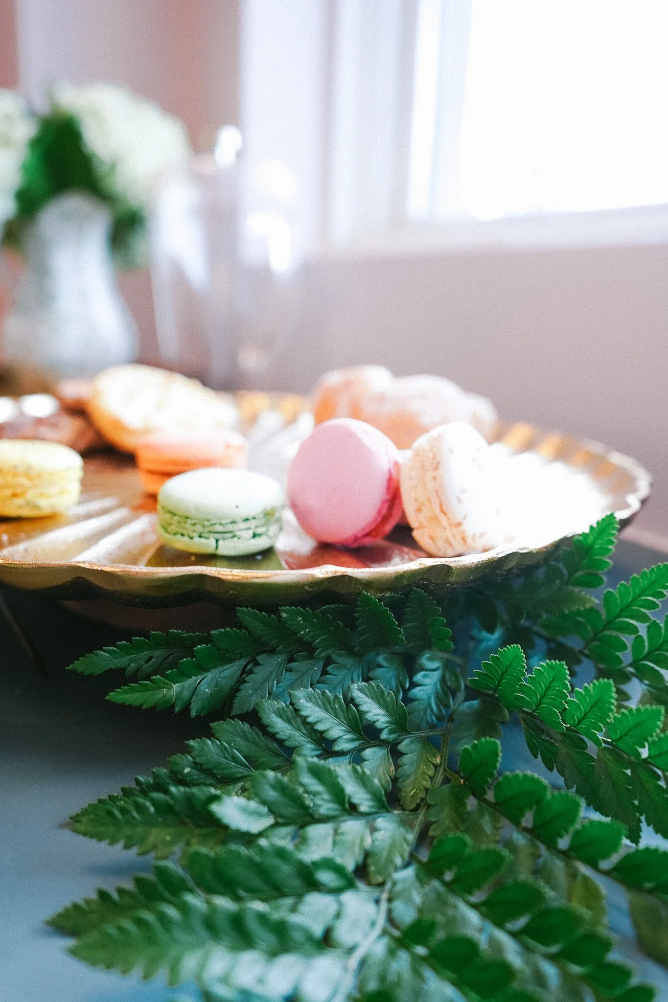 Gold decorative serving tray adorned with macaroons and greenery