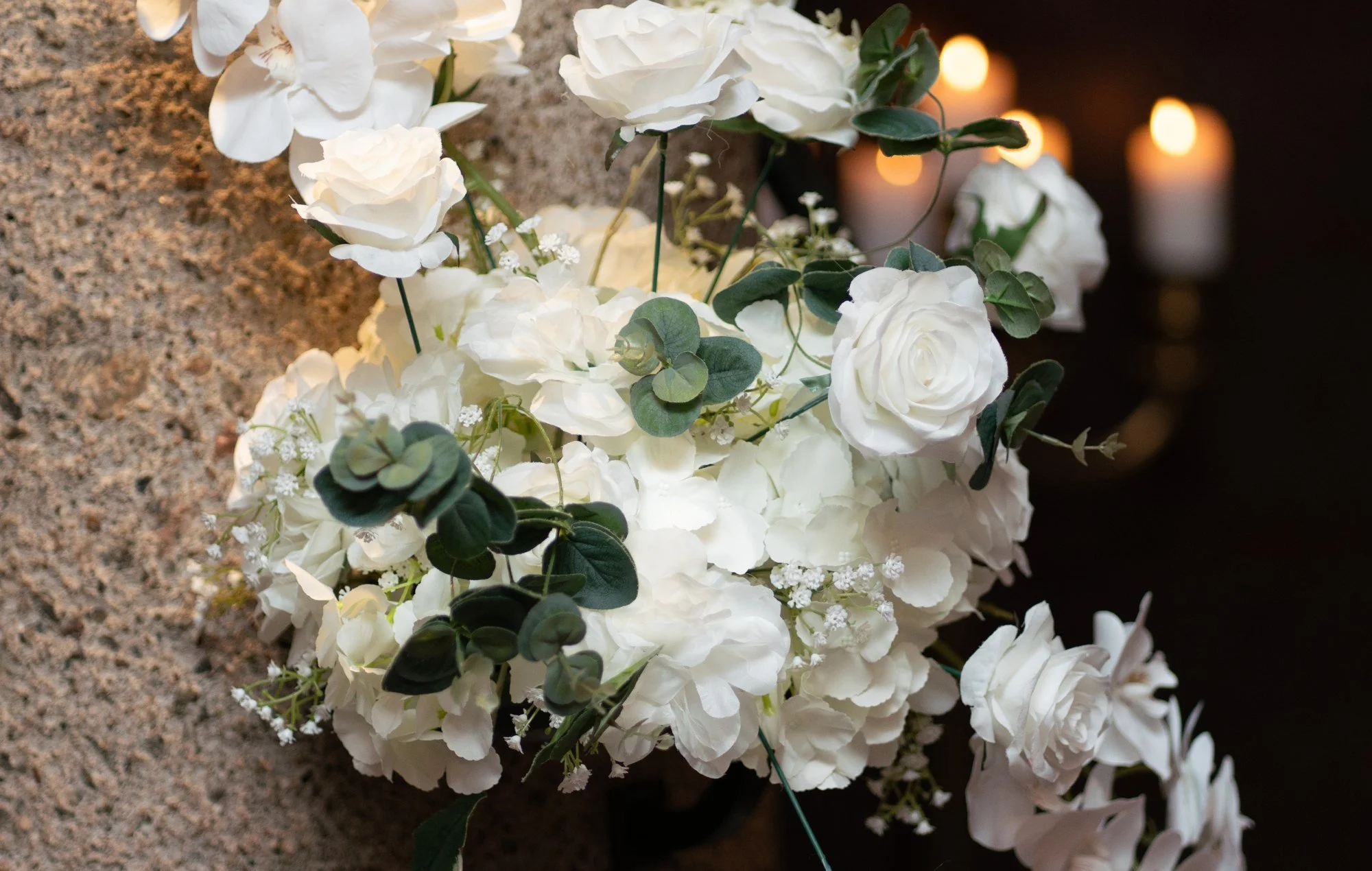 Vita rosor och små blommor i en bröllopsdekoration.