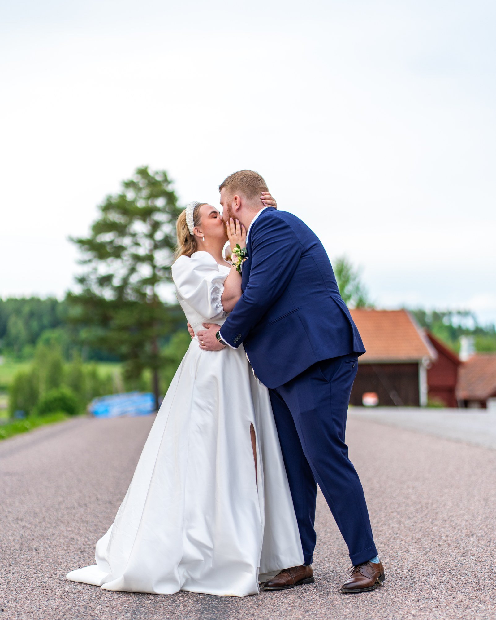 Brudpar kysser varandra utomhus med landskapet bakom sig.
