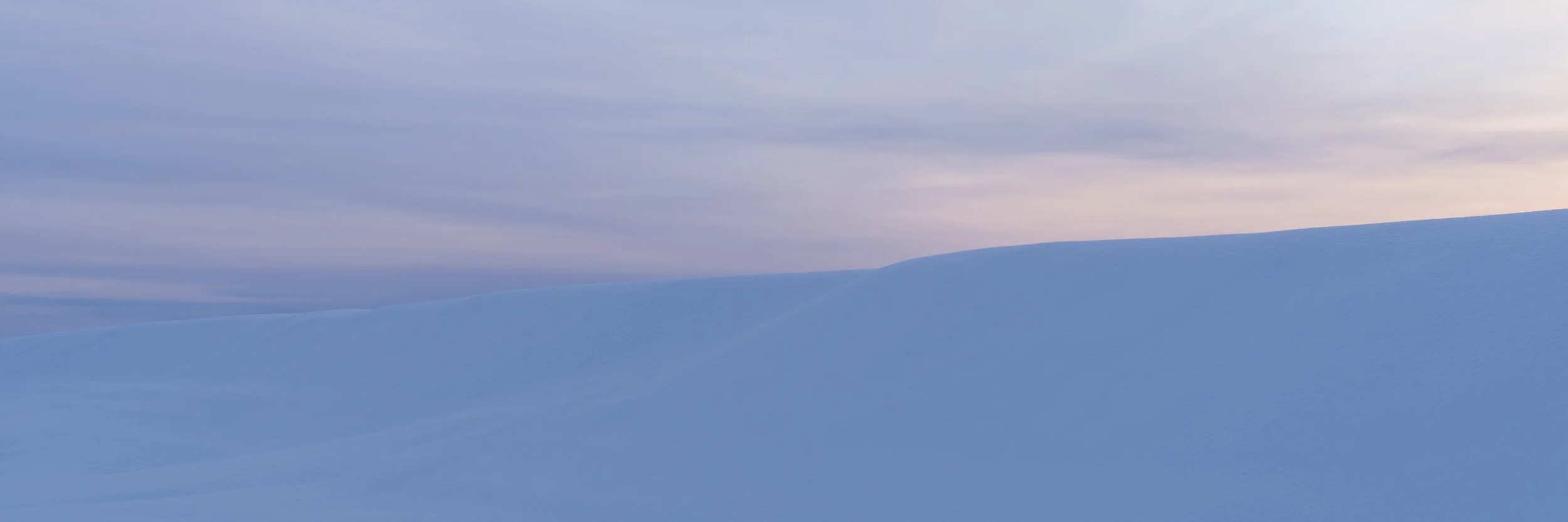 Minimalist Iceland winter landscape with blue snowfields, soft cloudy sky, and a quiet frozen horizon.