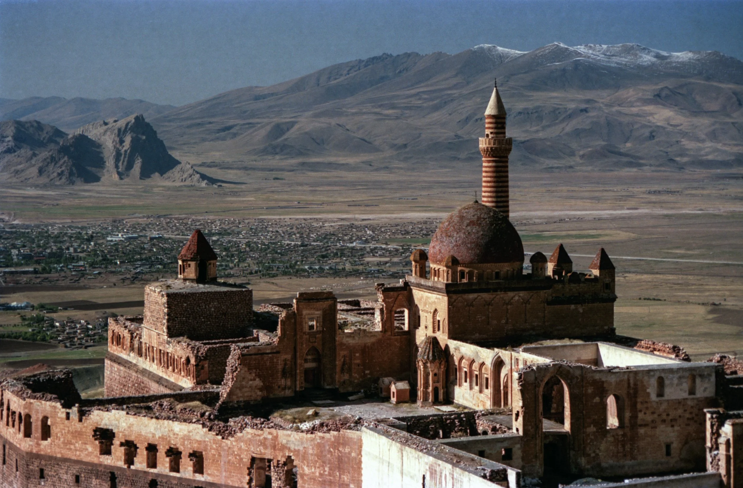 Historic mosque dome and minaret overlooking a rugged mountain valley in eastern Turkey.