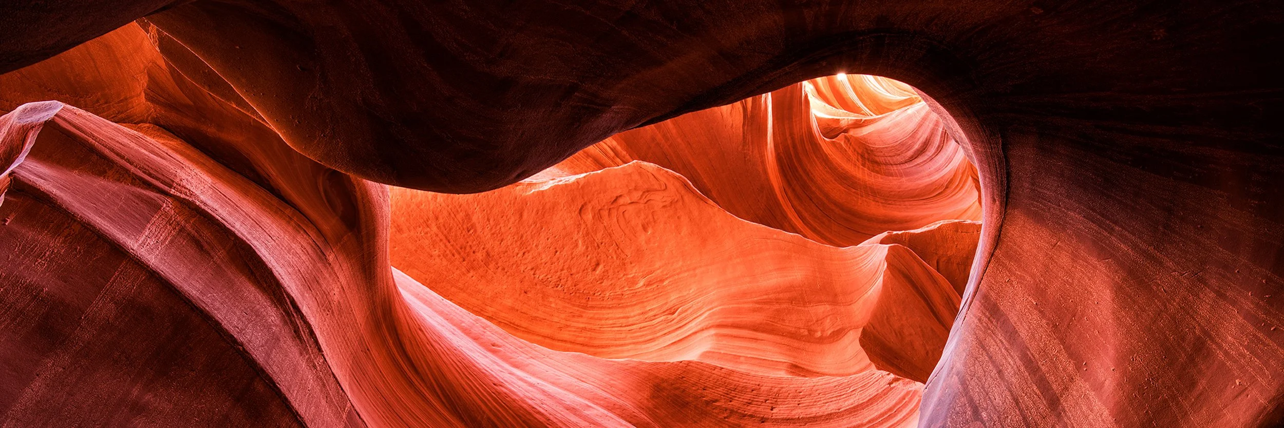 Glowing red sandstone curves inside Antelope Canyon, Arizona, showing dramatic light and sculpted slot canyon walls.