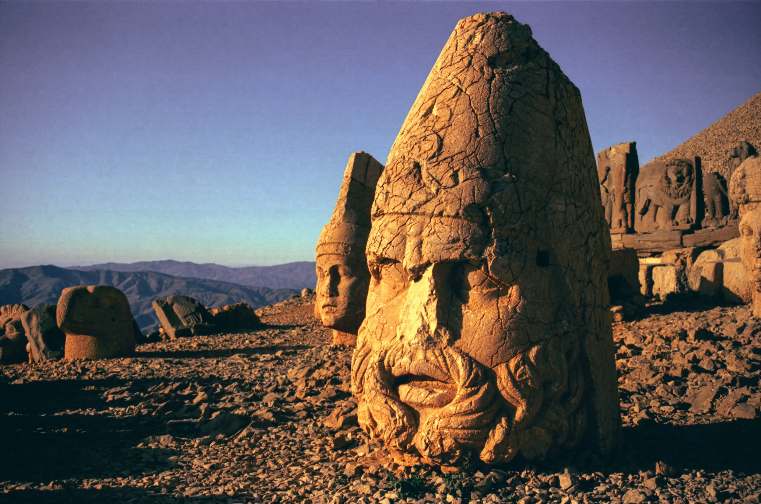 Ancient stone heads at Mount Nemrut lit by golden sunlight in eastern Turkey.