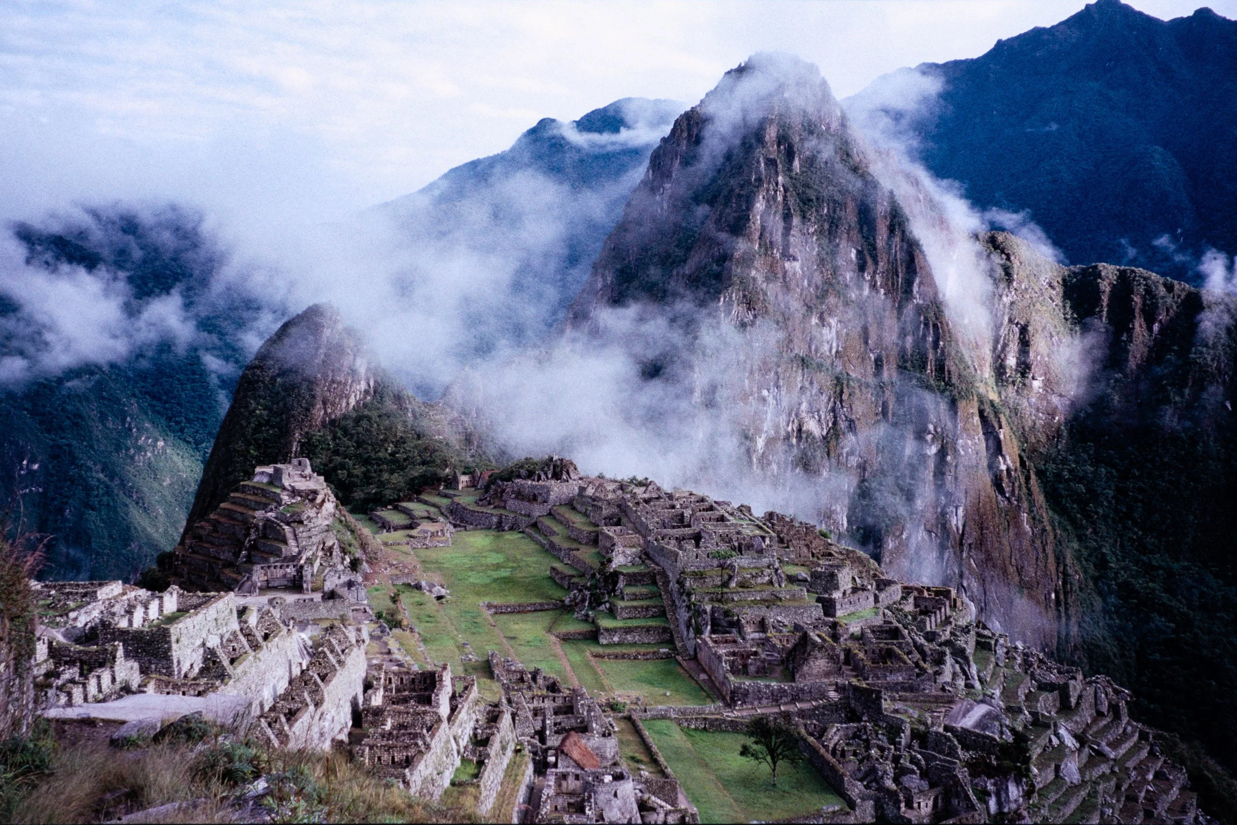 Machu Picchu ruins surrounded by misty Andes mountains and dramatic clouds in Peru.