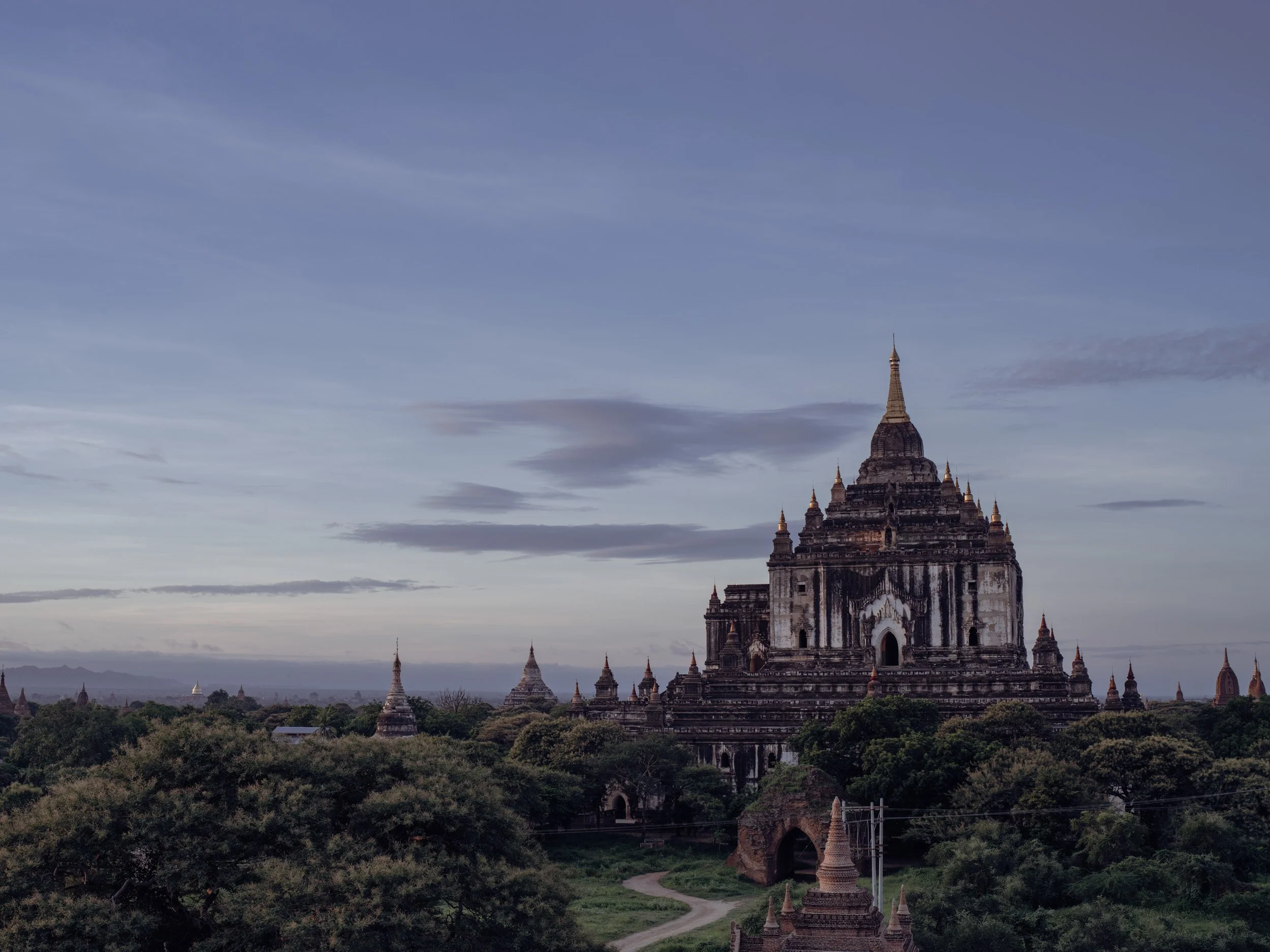 Bagan temple silhouette at blue hour with soft sky and distant pagodas in Myanmar.
