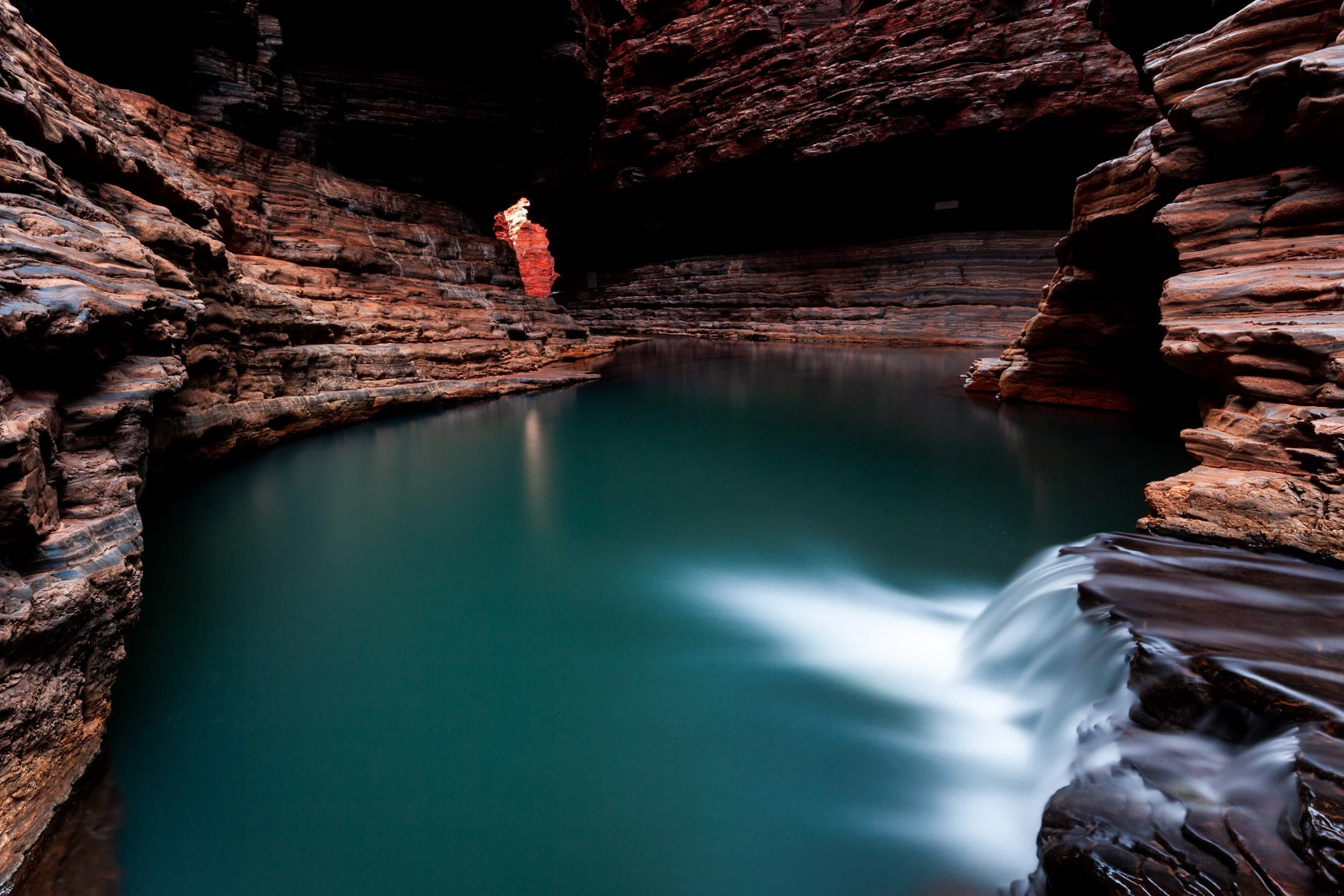 Turquoise water pool inside Hancock Gorge at Karijini National Park, Pilbara, with layered red rock walls and flowing water.