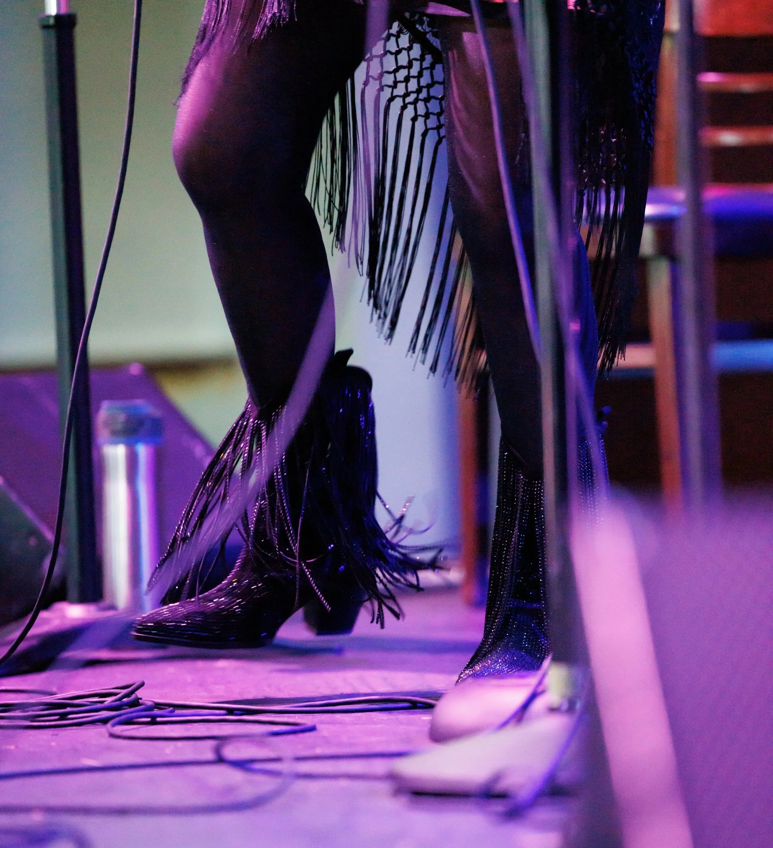 Black heeled boots with fringe standing on wires