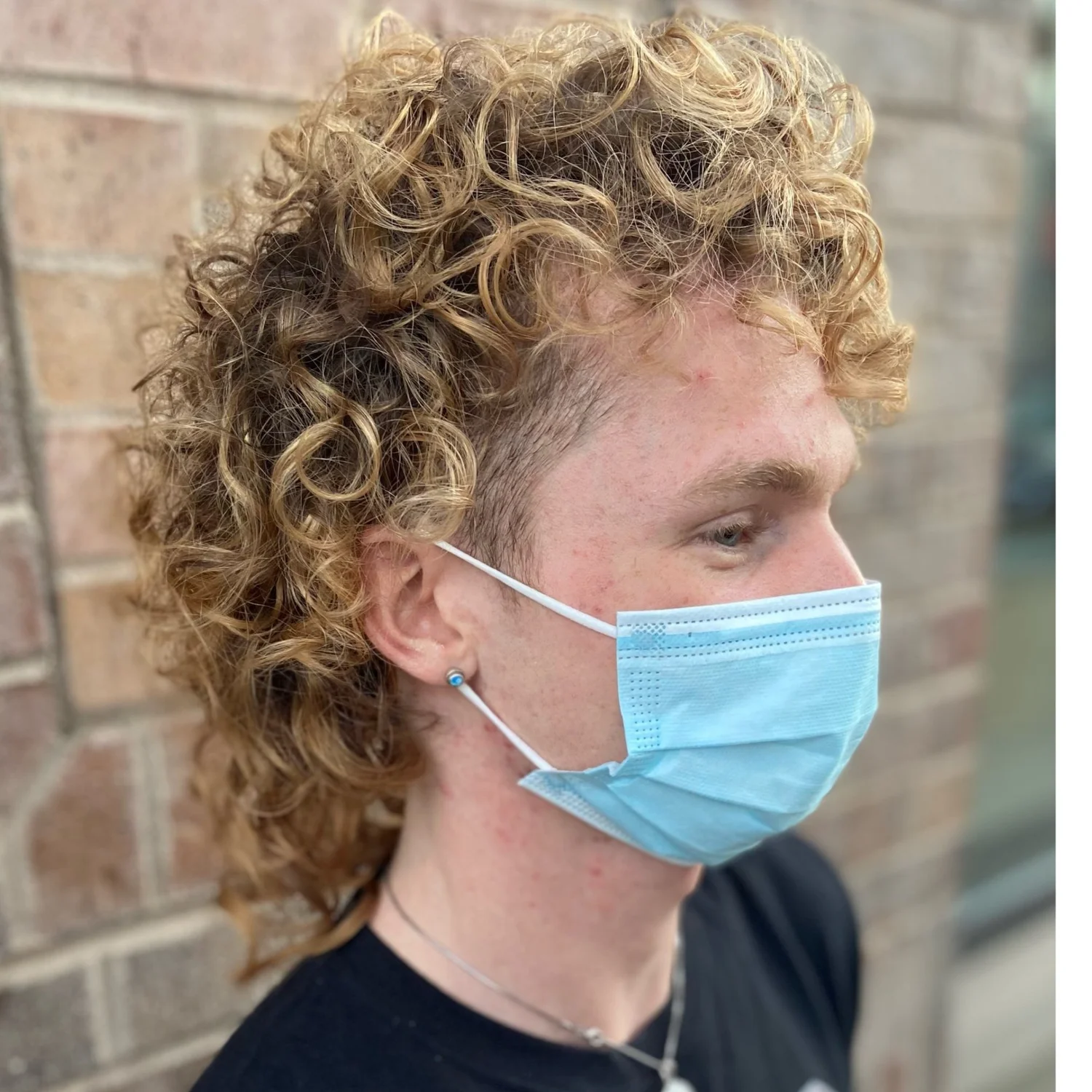 Curly blonde mullet on a client wearing a face mask