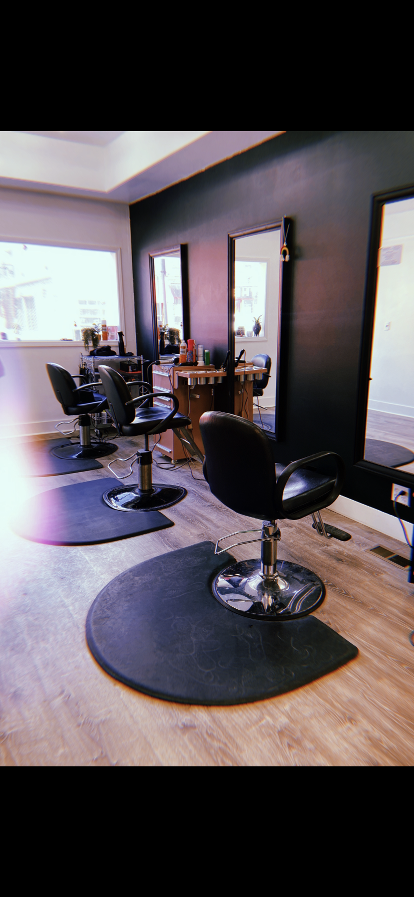 Salon styling stations with black chairs and mirrors