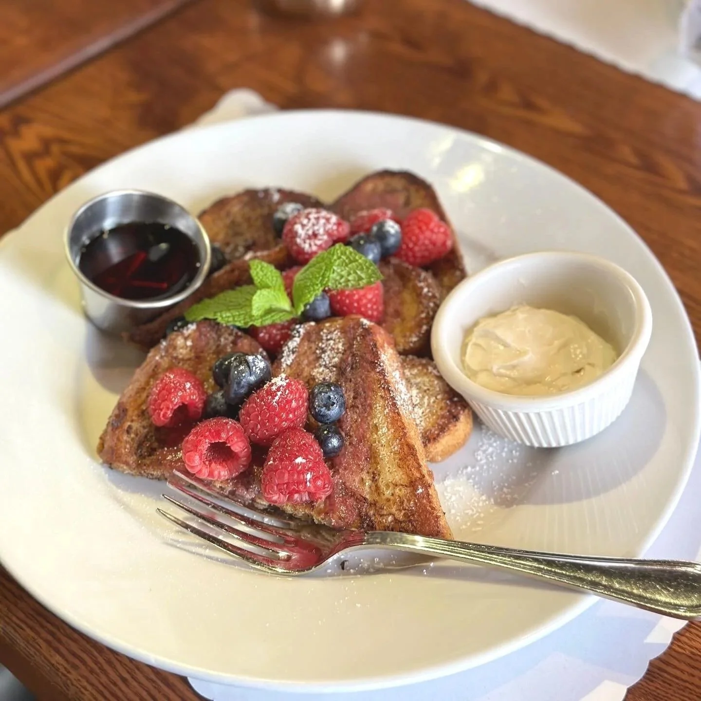 Brunch at Divina Cucina: French toast topped with mixed berries, mint, and powdered sugar, served with syrup and whipped butter.