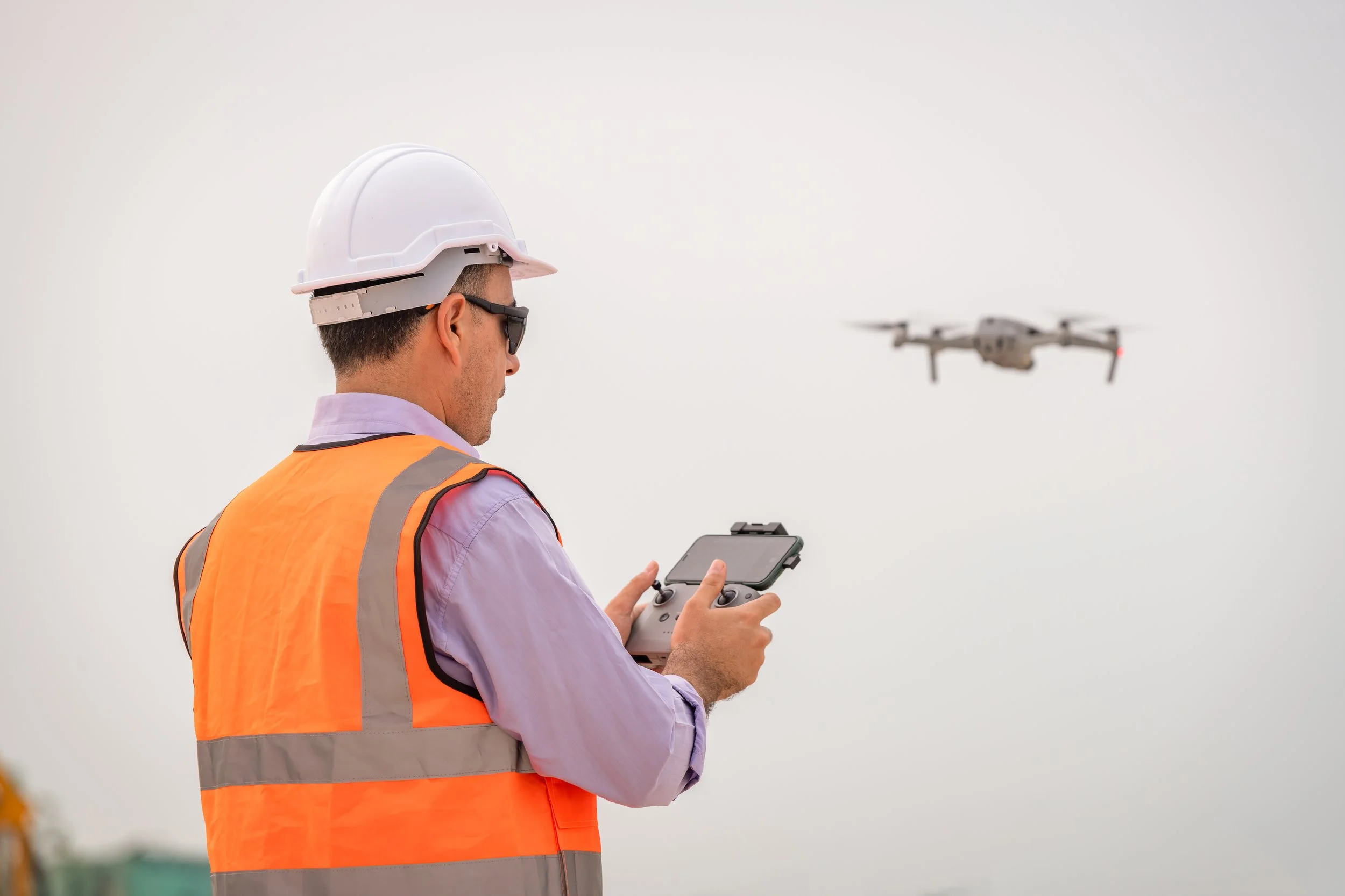 Drone pilot in hi-vis flying an inspection drone on site