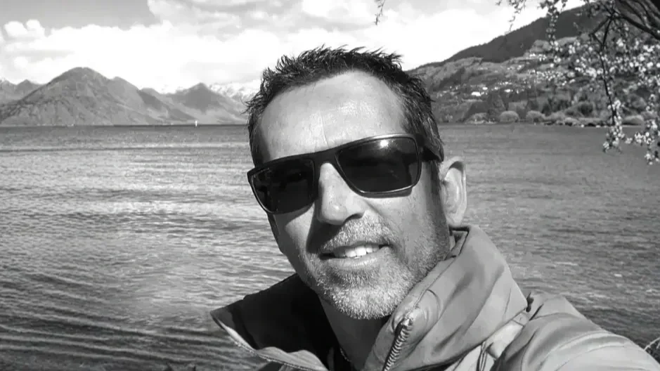 Man operating a camera on a tripod outside near a wall with the Astraea Aerospace logo.