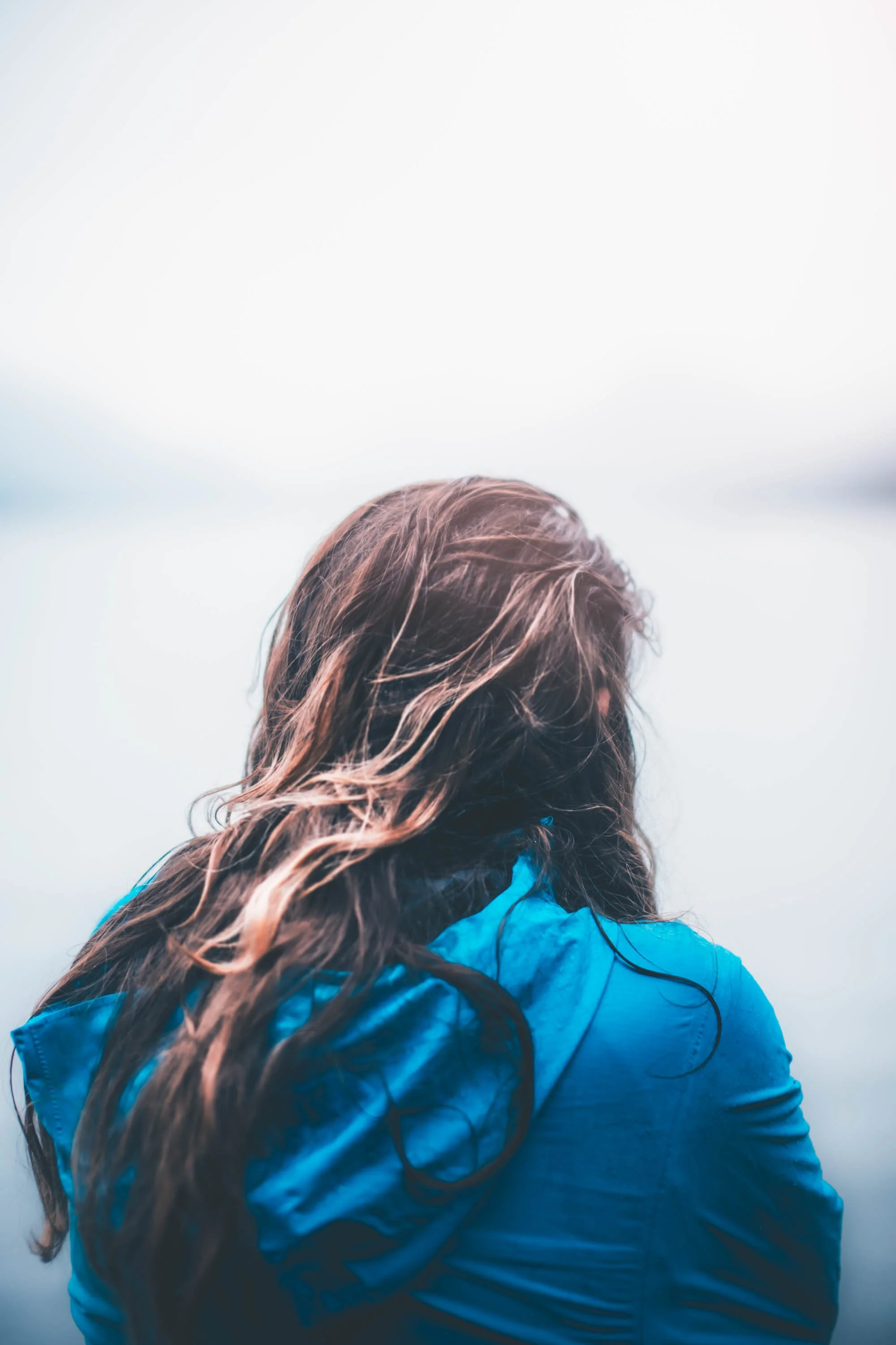 Smiling woman with long dark hair outdoors during autumn, holding a bottle, with blurred fall foliage in the background. Portrait by Archie Carmel.