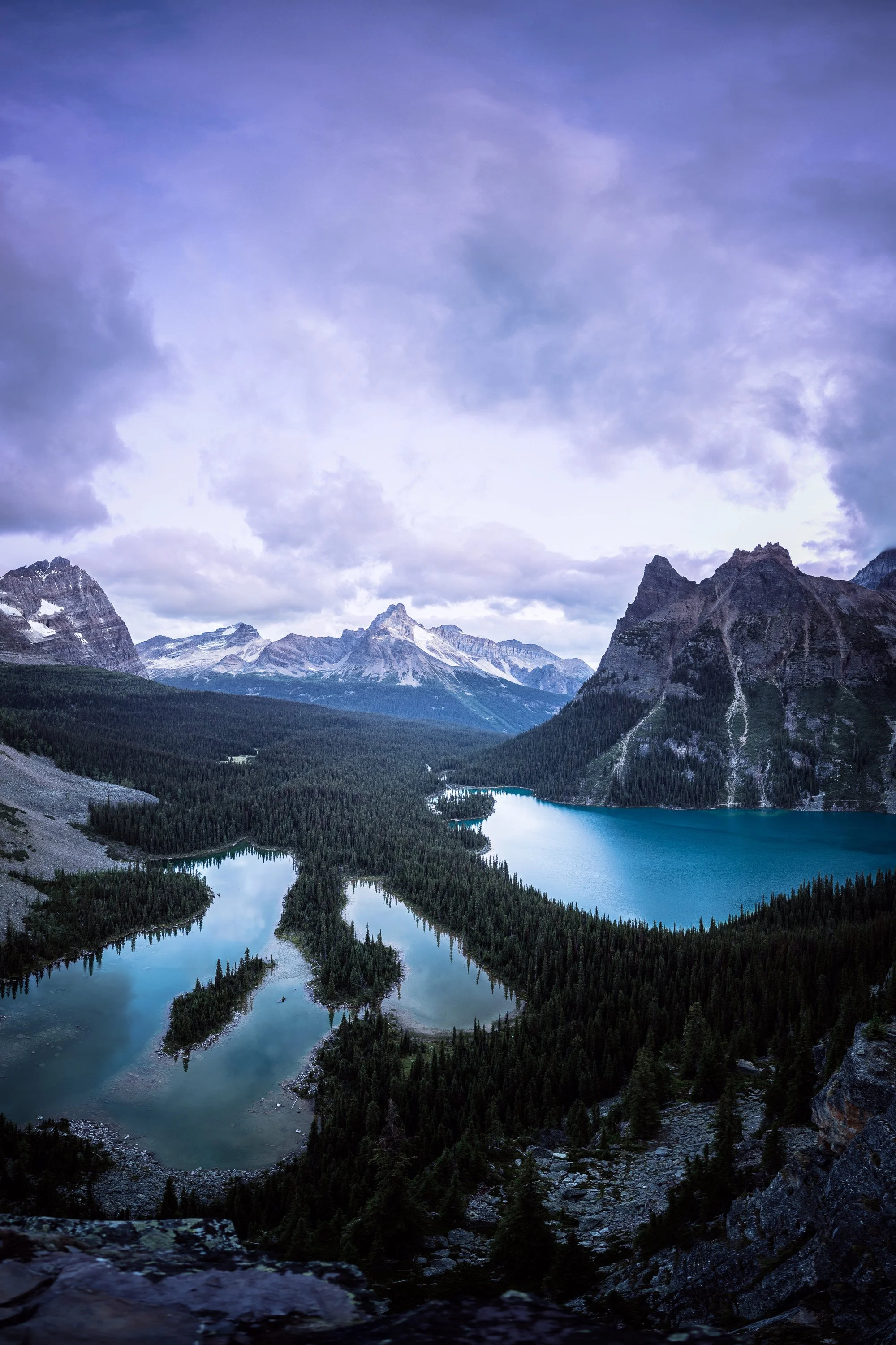 Sunset over many alpine lakes with dramatic clouds and Canadian Rocky Mountains in the foreground. By Archie Carmel.