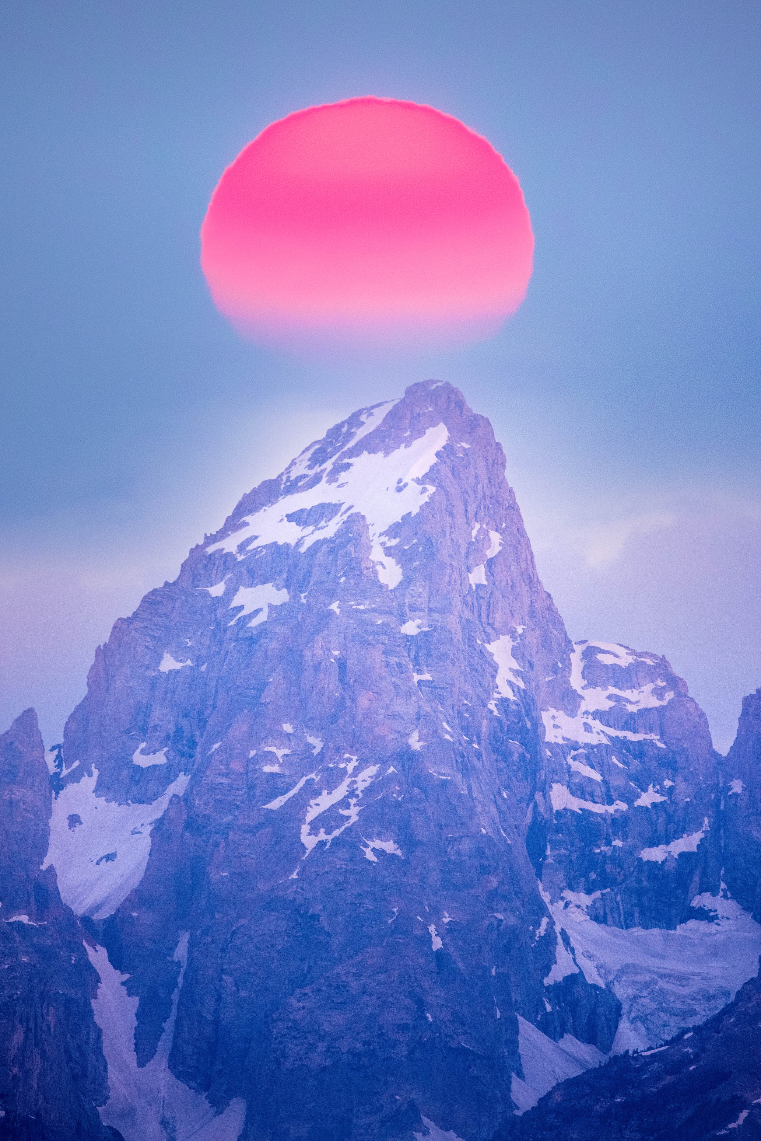 A close-up landscape view of Grand Teton mountain under fire red rising sun. By Archie Carmel.