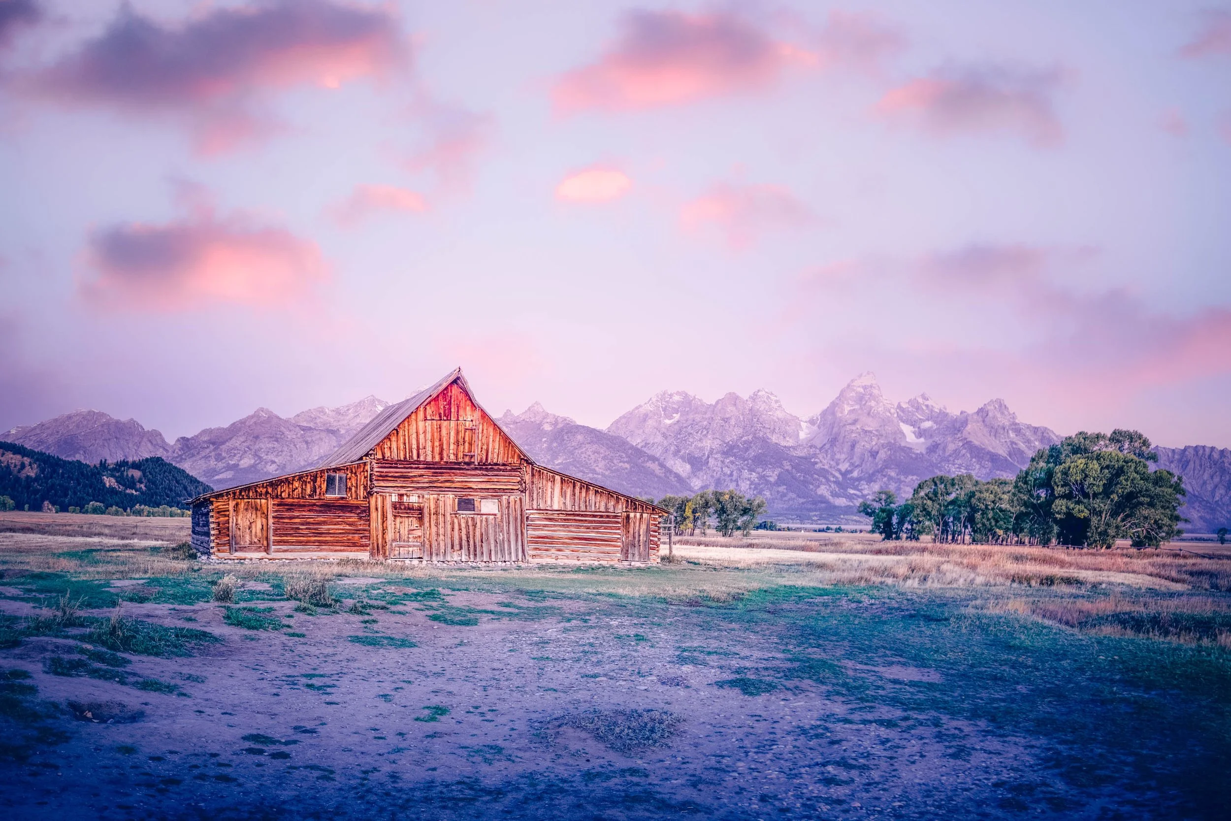 Close-up view of smooth, layered pink and purple old barn in a natural mountain landscape. By Archie Carmel.